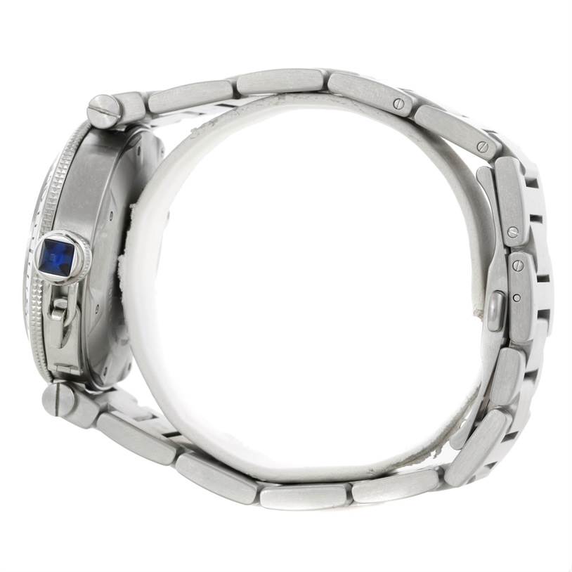 The image shows a side view of the Cartier Pasha W31077M7 Men
s Stainless Steel Black Dial W31077M7 Men
s Stainless Steel Black Dial watch, highlighting its crown with a blue gemstone and metal bracelet.