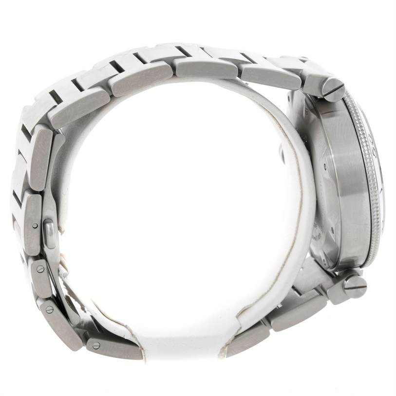The Pasha model by Cartier is shown from a side angle, highlighting its metal bracelet and the watch case.