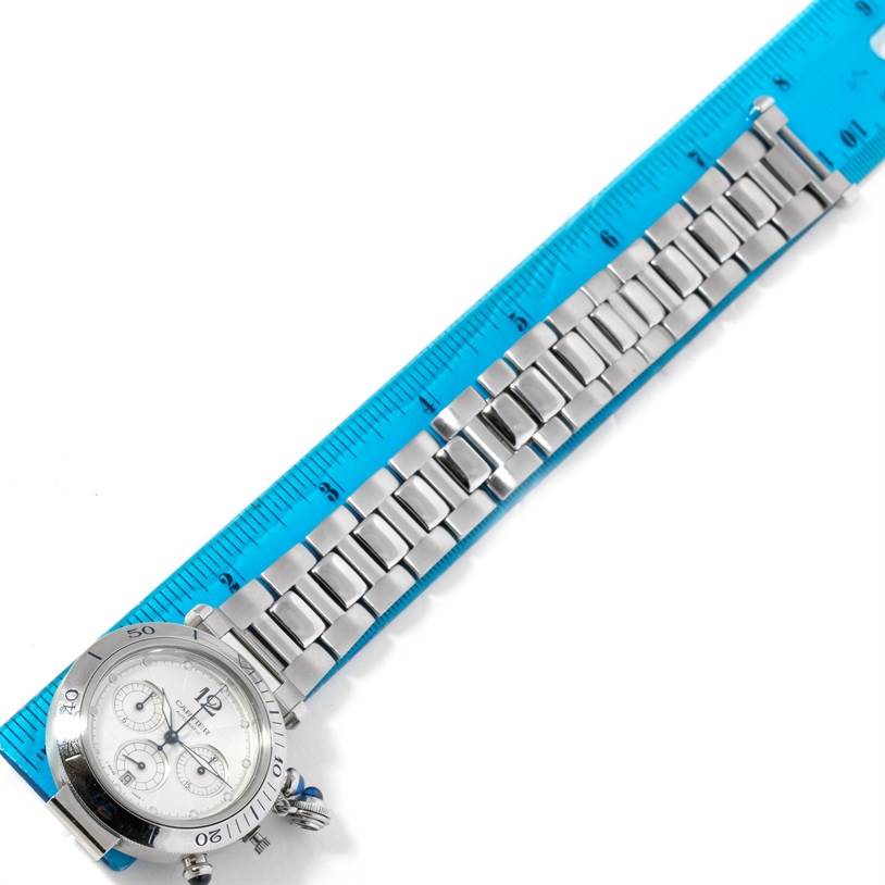 The image shows the face, bezel, and metal band of a Cartier Pasha W31030H3 Men's Stainless Steel Silver Dial W31030H3 Men's Stainless Steel Silver Dial watch alongside a blue ruler for measurement.