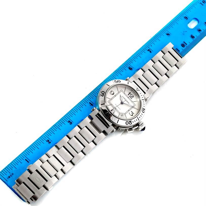 The Cartier Pasha W31080M7 Men's Stainless Steel Silver Dial W31080M7 Men's Stainless Steel Silver Dial watch is shown from above, displaying its face, bezel, and bracelet next to a blue ruler for scale.