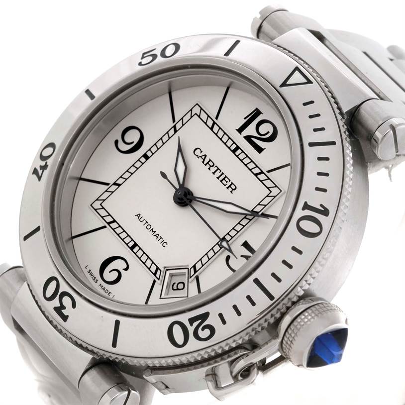 The image shows a close-up angle of the Cartier Pasha W31080M7 Men's Stainless Steel Silver Dial W31080M7 Men's Stainless Steel Silver Dial watch, focusing on its face, bezel, and signature crown with a blue gemstone.