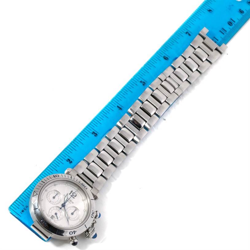 The Cartier Pasha W31030H3 Men
s Stainless Steel Silver Dial W31030H3 Men
s Stainless Steel Silver Dial watch is shown from the top angle, displaying its face and metal bracelet next to a measuring ruler.