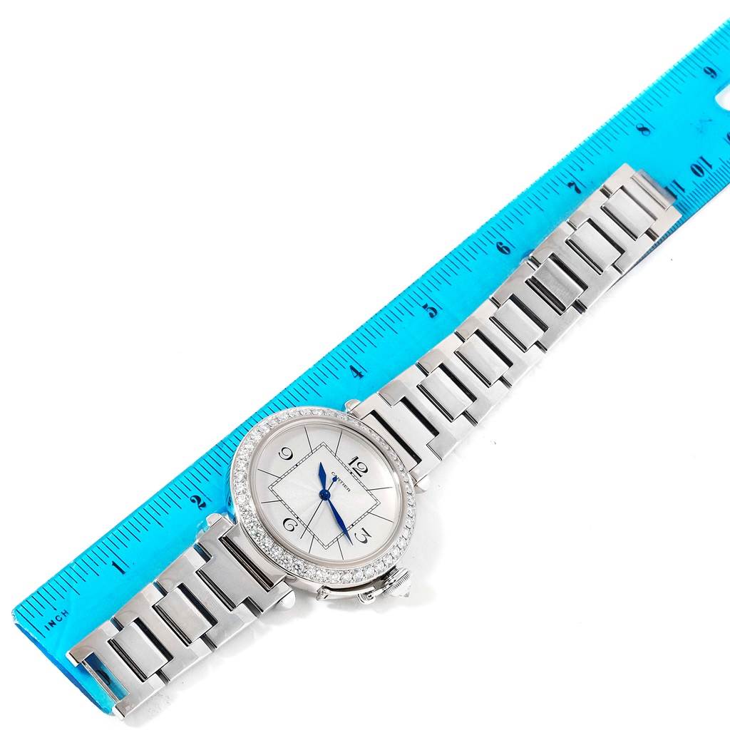 The Cartier Pasha WJ1202M9 Men's White Gold Silver Dial WJ1202M9 Men's White Gold Silver Dial watch is shown lying flat with its entire bracelet and face visible next to a blue ruler.