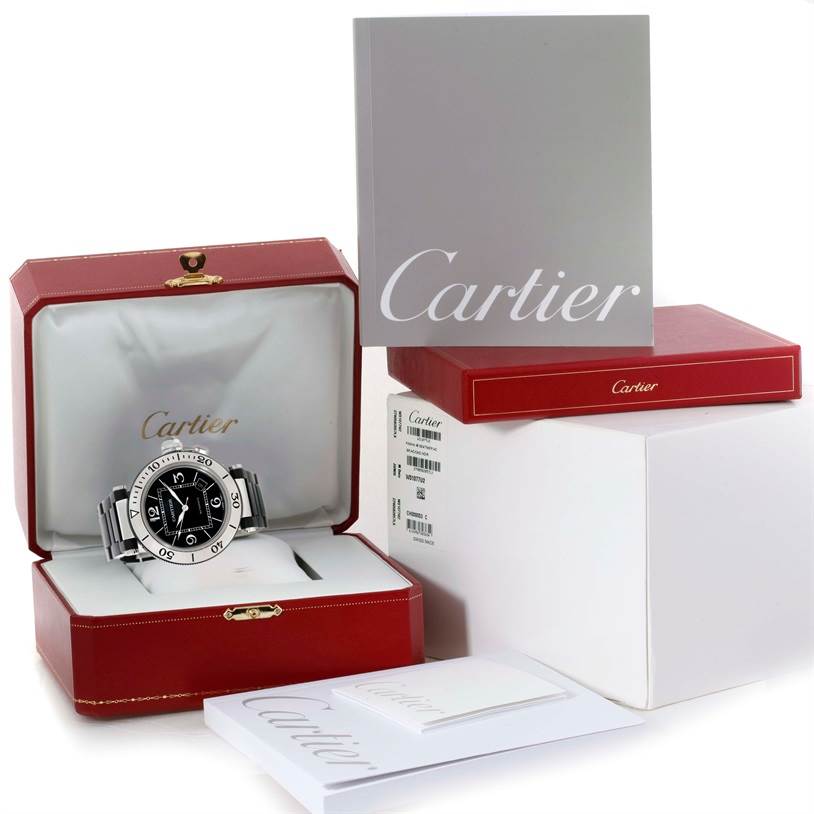 The Cartier Pasha W31077U2 Men's Stainless Steel Black Dial W31077U2 Men's Stainless Steel Black Dial watch is shown in its open red box along with additional packaging and manuals placed around it.