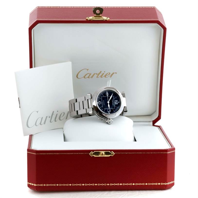 The Cartier Pasha W31076M7 Women's Stainless Steel Black Dial W31076M7 Women's Stainless Steel Black Dial watch is displayed in its open case, showing the face and part of the bracelet, with accompanying documentation.