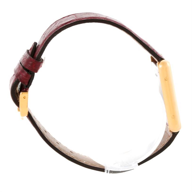 This image shows a side view of a Cartier Tank Solo W1018755 Women's Steel and Gold (two tone) Silver Dial W1018755 Women's Steel and Gold (two tone) Silver Dial watch, highlighting its gold rectangular case and maroon leather strap.