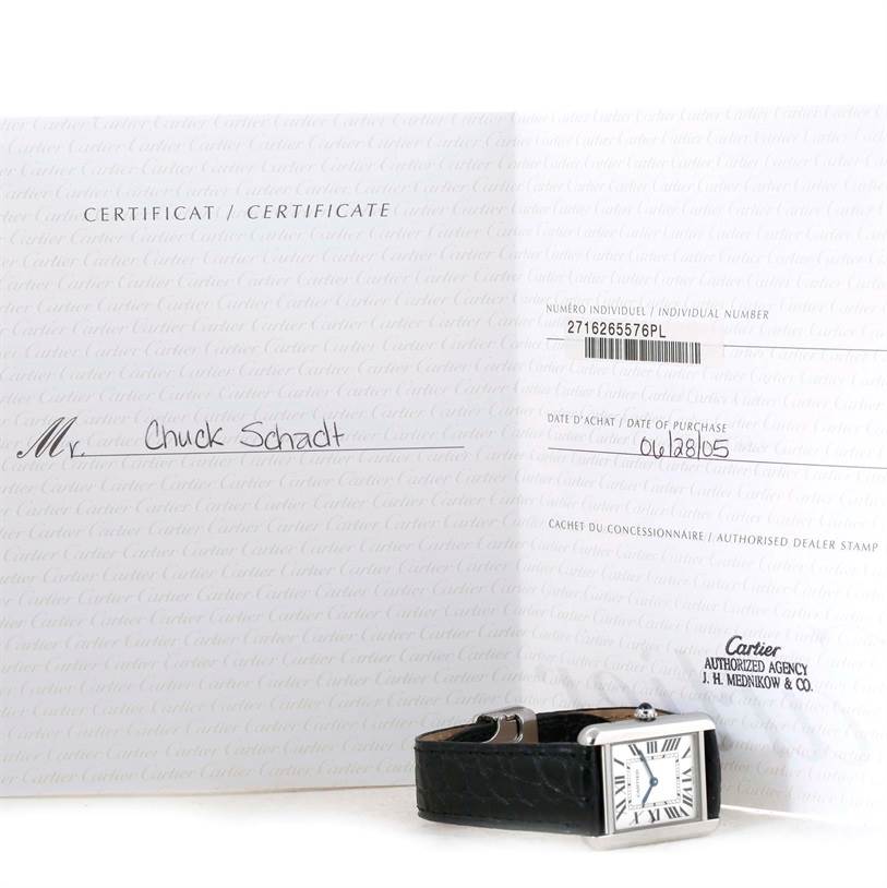 The image shows a Cartier Tank Solo W1018255 Women's Stainless Steel Silver Dial W1018255 Women's Stainless Steel Silver Dial watch laid flat with its certificate of authenticity propped open behind it.