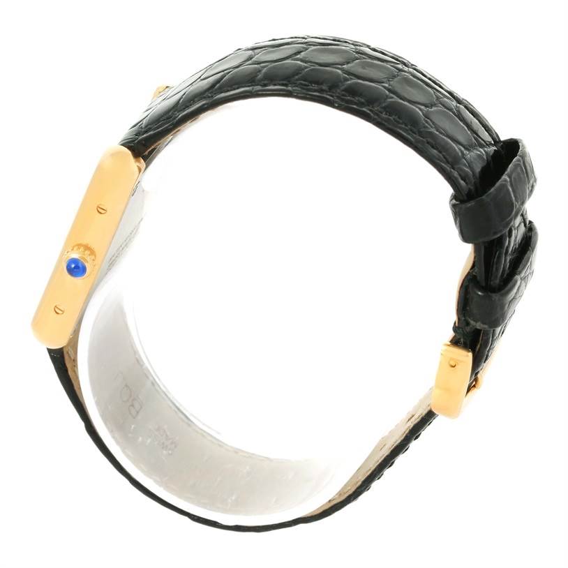 The image shows a Tank Solo watch by Cartier from a side angle, highlighting its leather strap and gold side case with a blue gem-set crown.