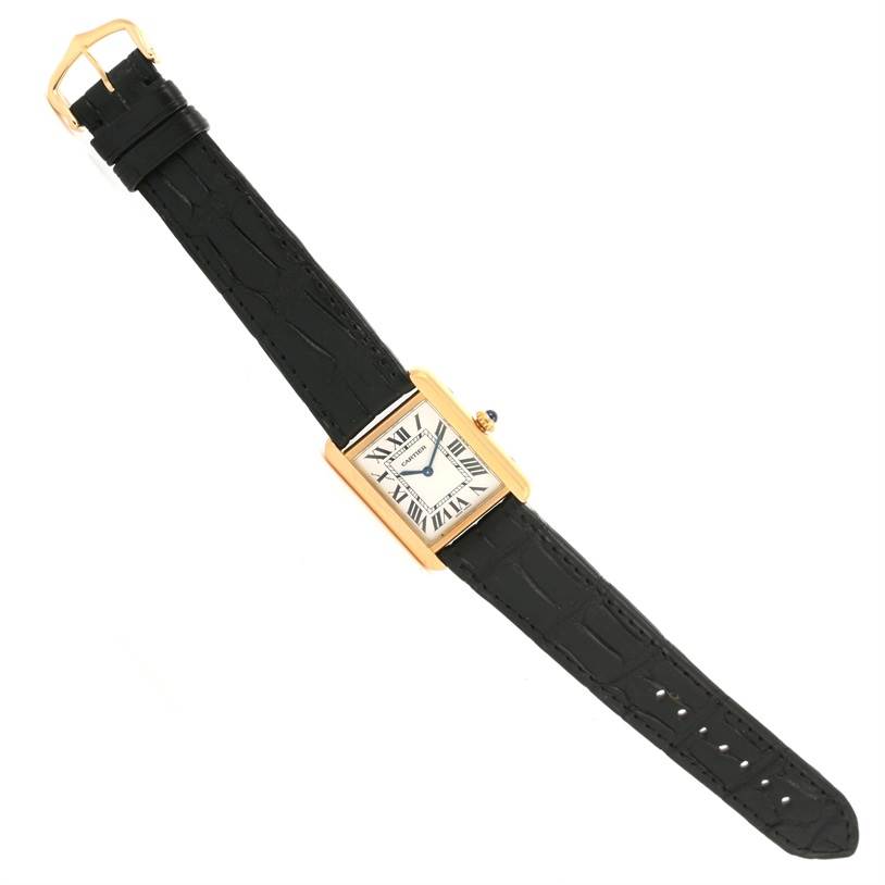 The Tank Solo model by Cartier is shown from a top-down angle, showcasing its black leather strap and rectangular gold case with a white dial.