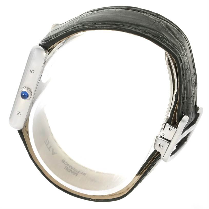 The image shows a side view of the Cartier Tank Solo W1018255 Women
s Stainless Steel Silver Dial W1018255 Women
s Stainless Steel Silver Dial watch, highlighting the blue cabochon crown and black leather strap.