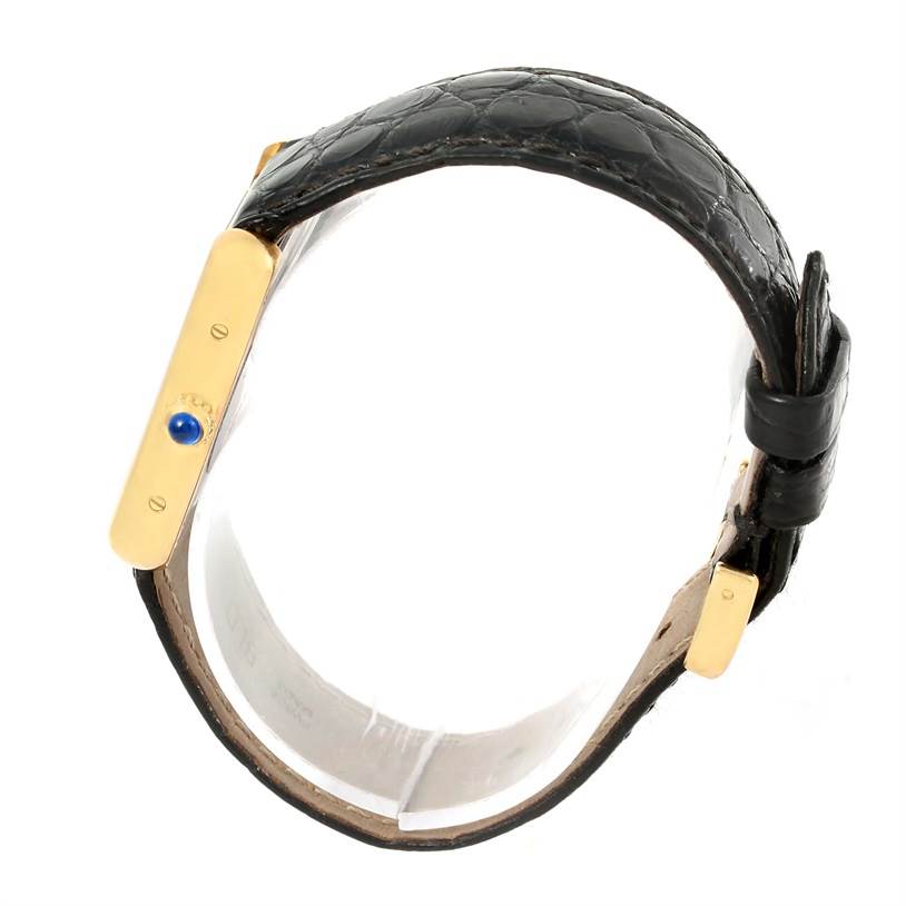 This image shows a side profile view of the Tank Solo watch by Cartier, highlighting the golden side case and blue cabochon crown.