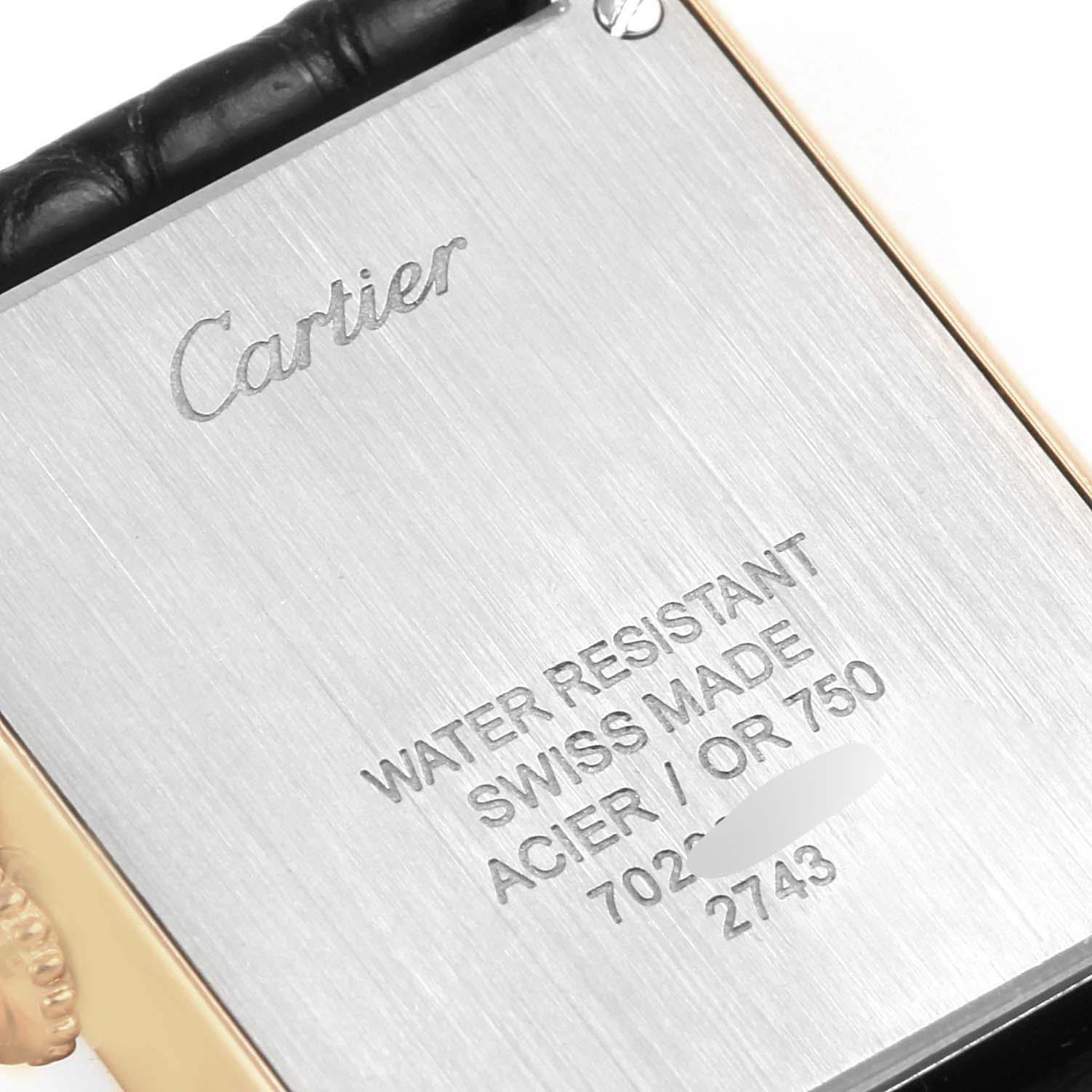 The image shows the back case of a Cartier Tank Solo W1018755 Women
s Steel and Gold (two tone) Silver Dial W1018755 Women
s Steel and Gold (two tone) Silver Dial watch, highlighting its engraved details and attached strap.