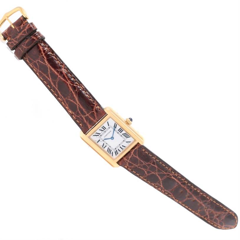 The Tank Solo model by Cartier is shown from a top-down angle, displaying its rectangular face and leather strap.