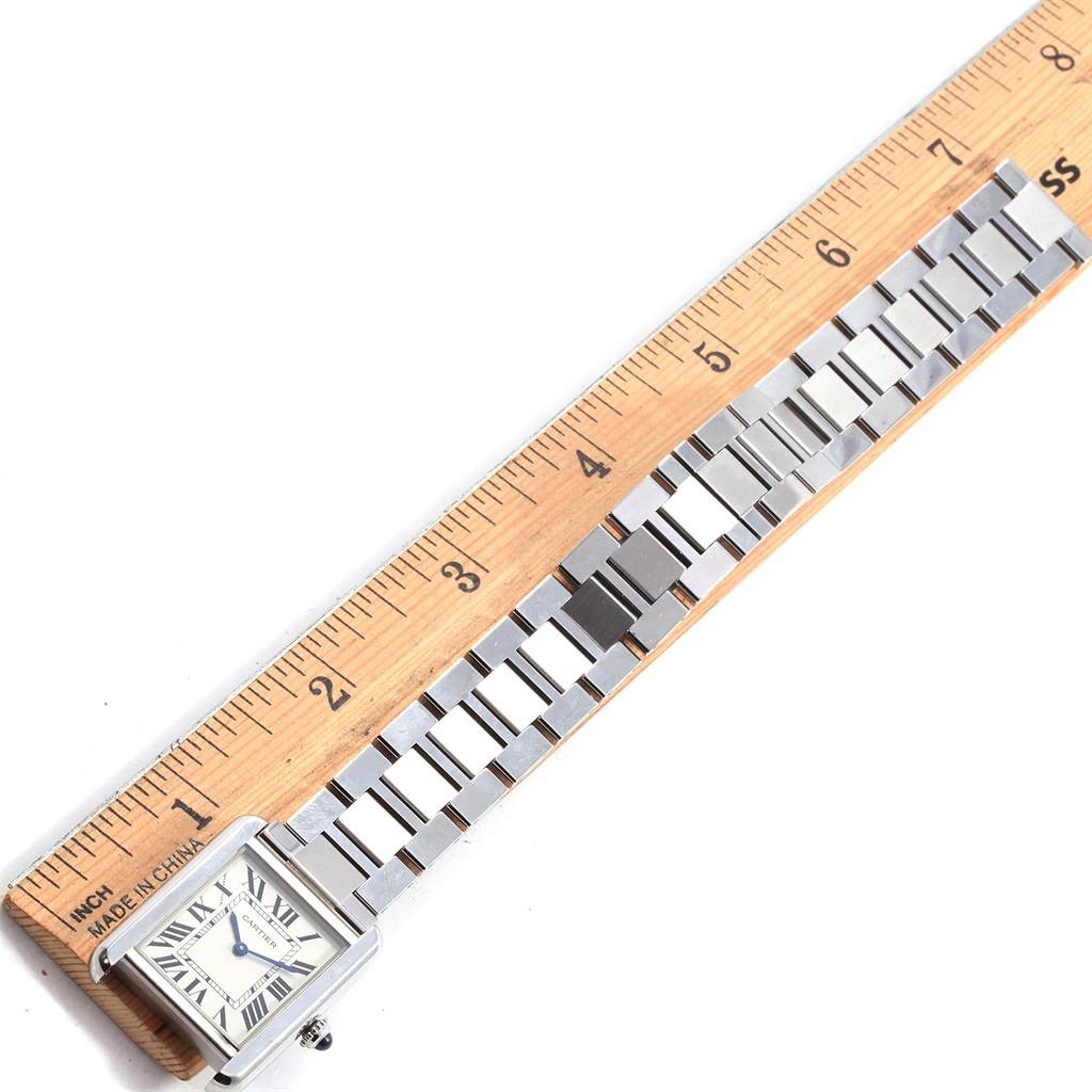 The Cartier Tank Solo W5200013 Women
s Stainless Steel Silver Dial W5200013 Women
s Stainless Steel Silver Dial watch is shown from the top with the face and bracelet partially measured against a wooden ruler.