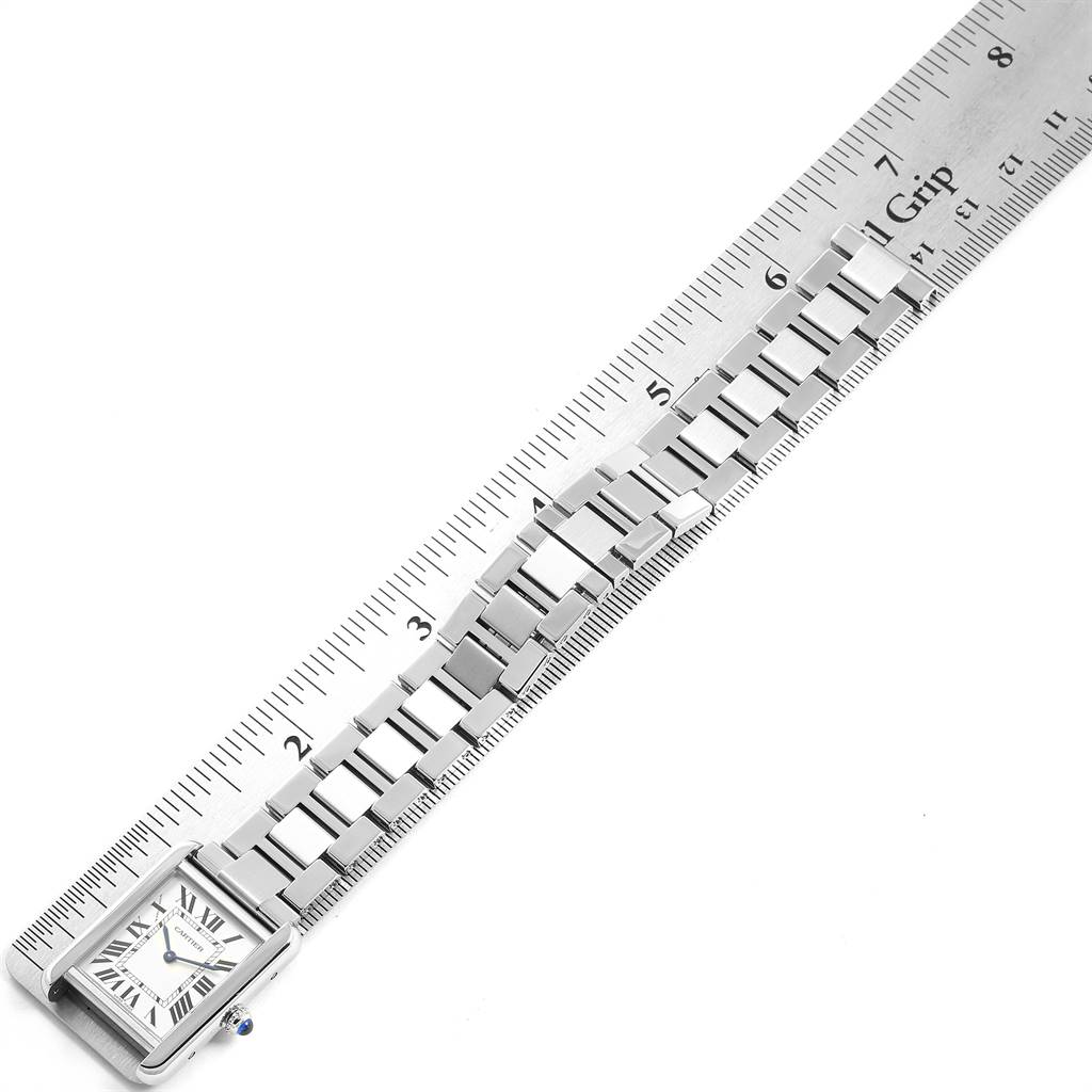 The image shows the Tank Solo model by Cartier, featuring its rectangular dial and stainless steel bracelet measured against a ruler.