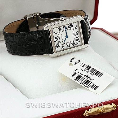 This Cartier Tank Solo W1018255 Women's Stainless Steel Silver Dial W1018255 Women's Stainless Steel Silver Dial watch is displayed from an oblique angle, showing its square face, black leather strap, and a tag with branding.