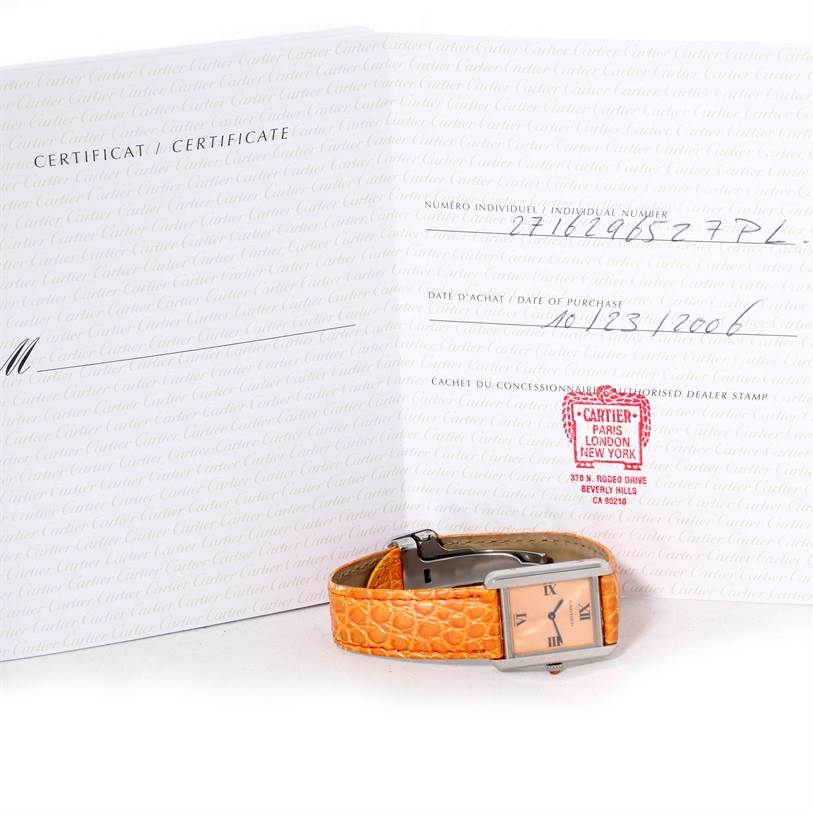 The image shows a Cartier Tank Solo W1019455 Women's Stainless Steel Orange Dial W1019455 Women's Stainless Steel Orange Dial watch with an orange strap, placed in front of its certificate of authenticity.