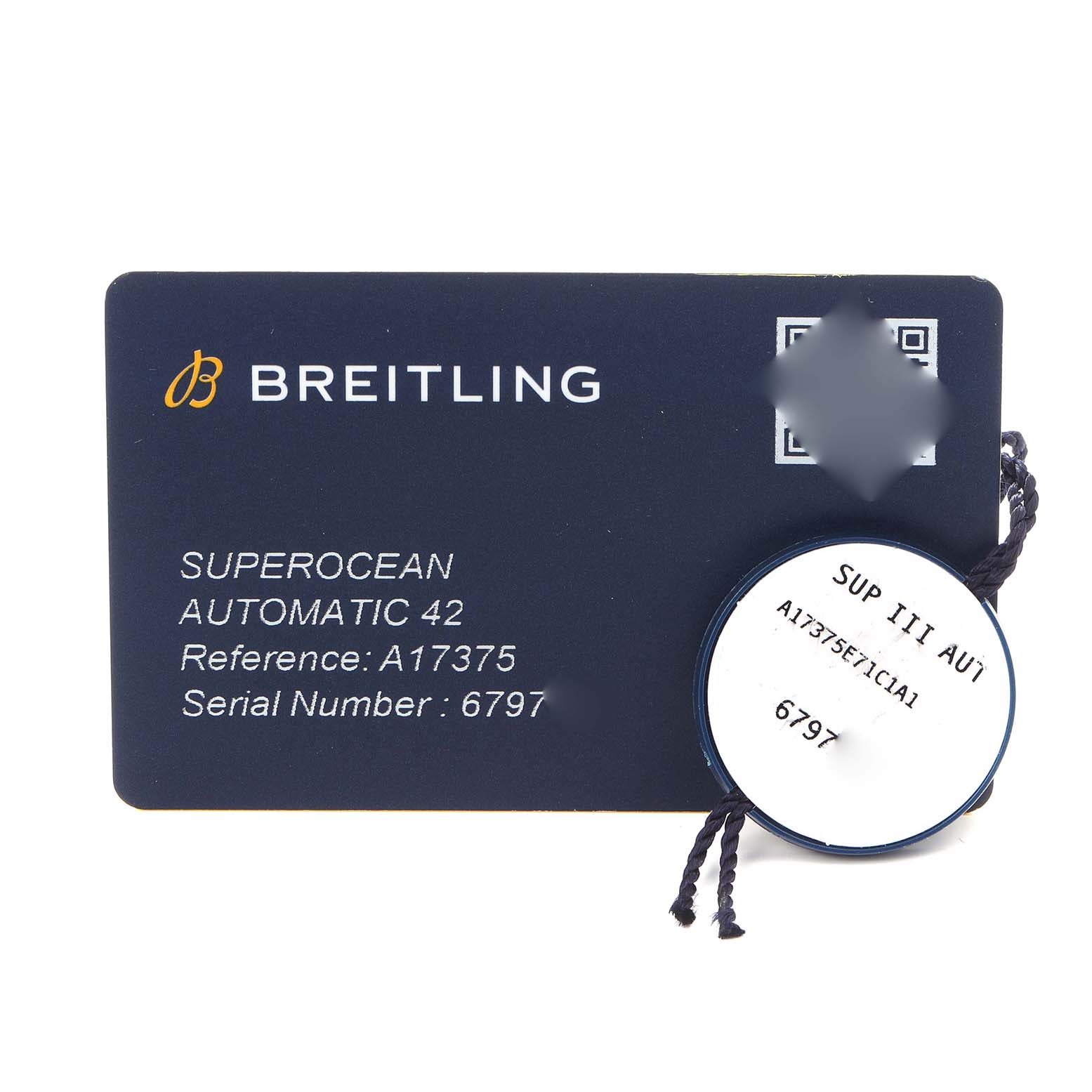 The image shows a Breitling Superocean A17375 Men
s Stainless Steel Blue Dial A17375 Men
s Stainless Steel Blue Dial model card with reference and serial numbers, alongside a round tag on a string.