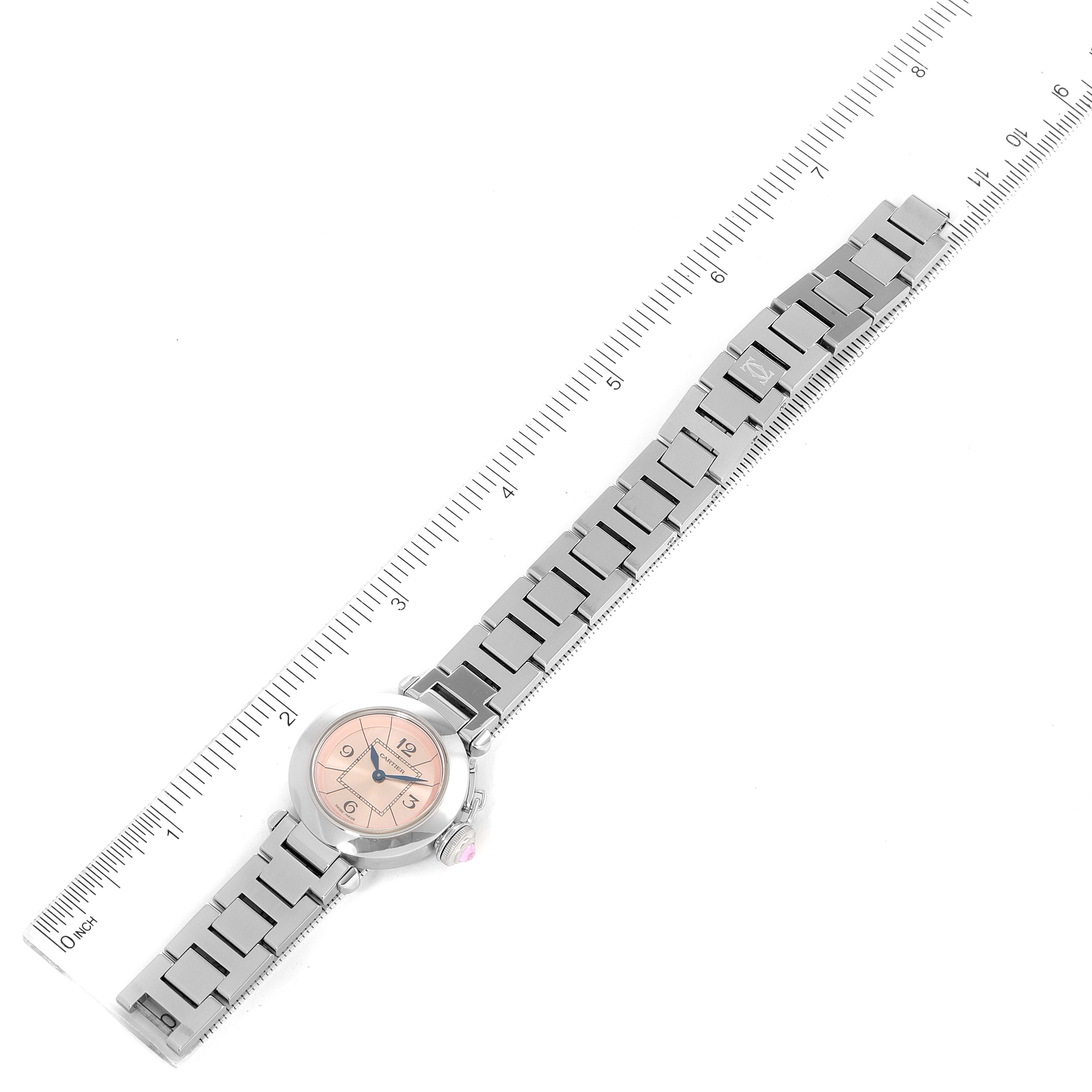 The image shows a top-down view of a Cartier Pasha W3140008 Women's Stainless Steel Pink Dial W3140008 Women's Stainless Steel Pink Dial watch with a metallic band and a surrounding ruler for measurement.