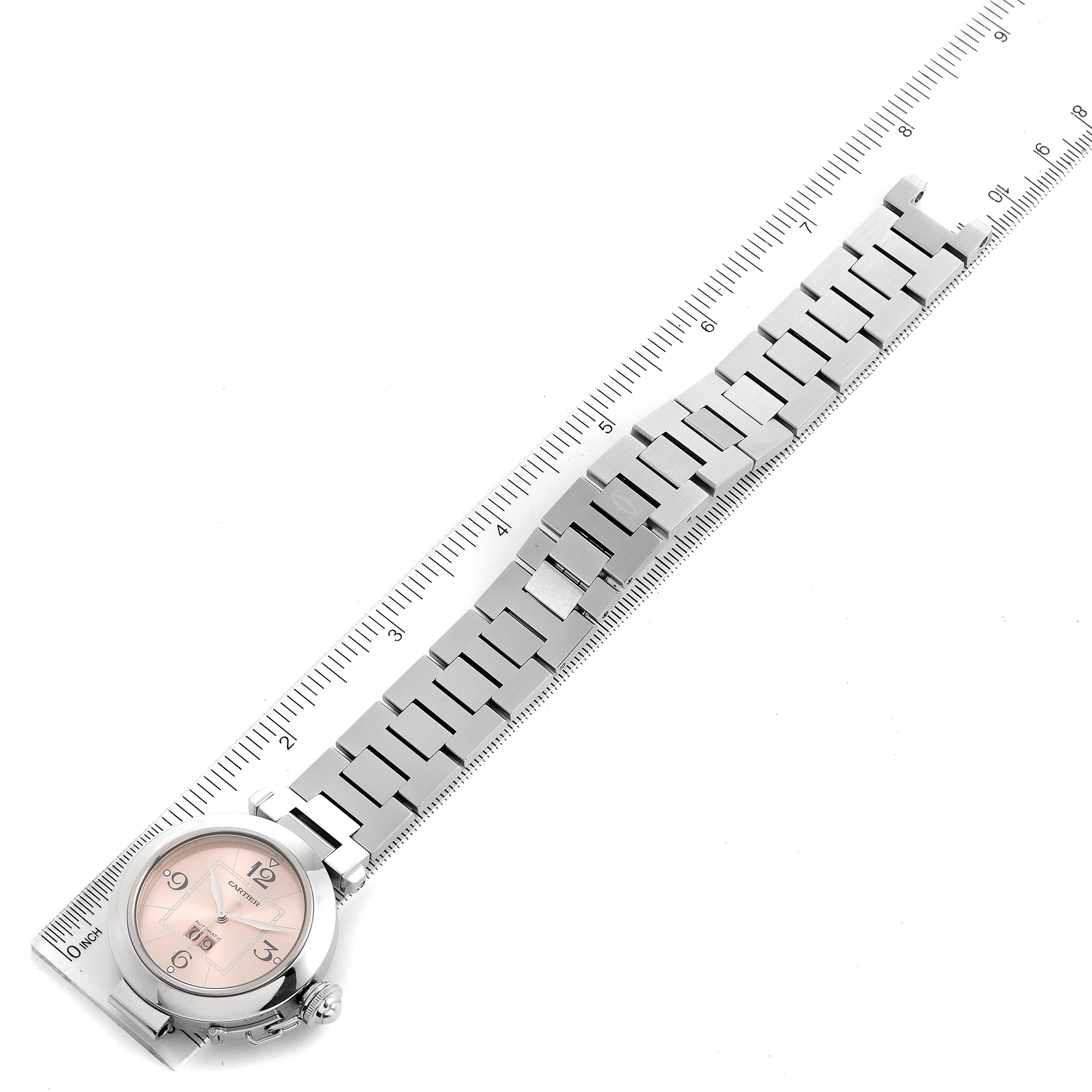 The image shows the entire Pasha model watch by Cartier, including its watch face and metal bracelet, laid alongside a measuring ruler.