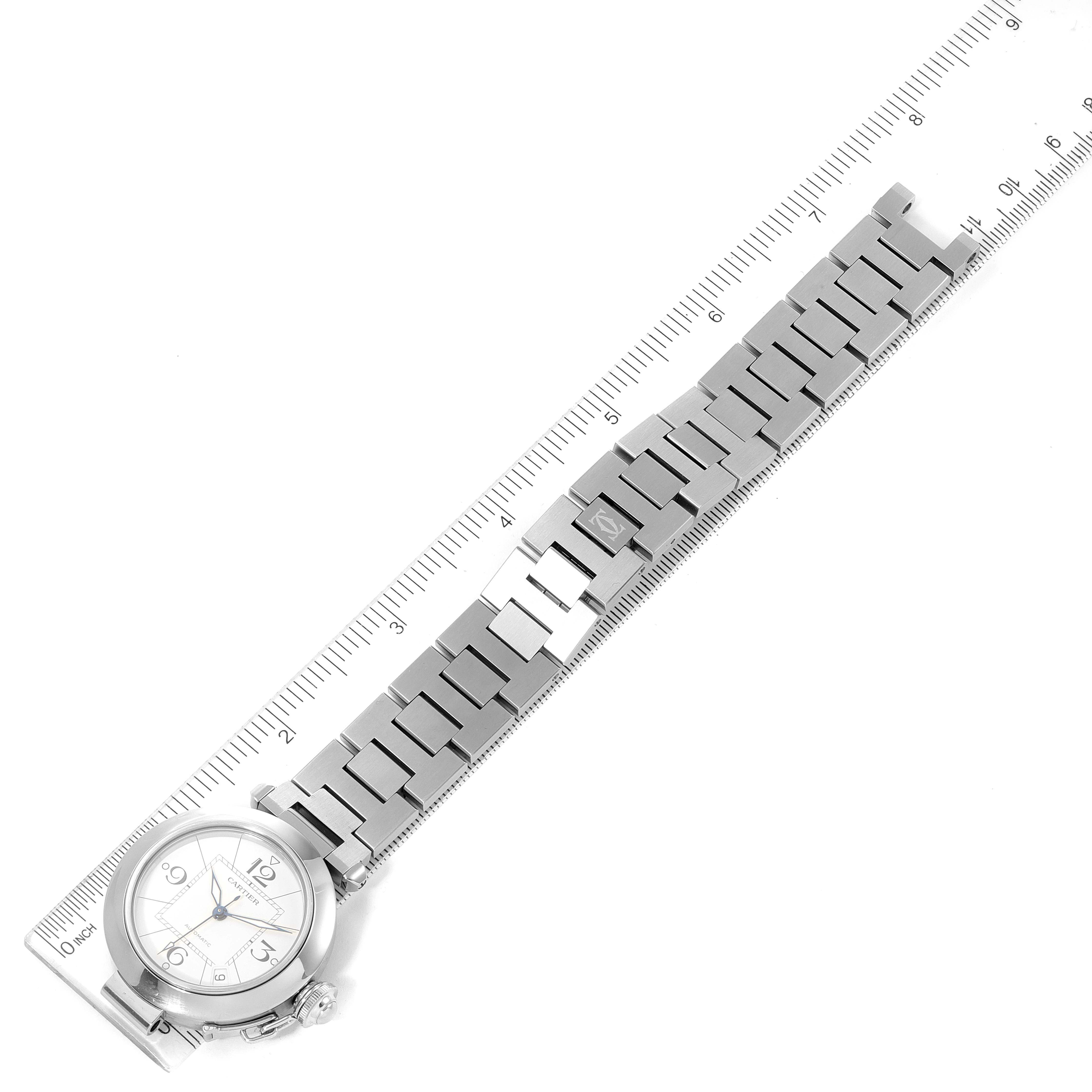 The image shows the Cartier Pasha W31074M7 Men's Stainless Steel White Dial W31074M7 Men's Stainless Steel White Dial watch from a top-down angle, highlighting its metal bracelet and round watch face along with a ruler for scale.