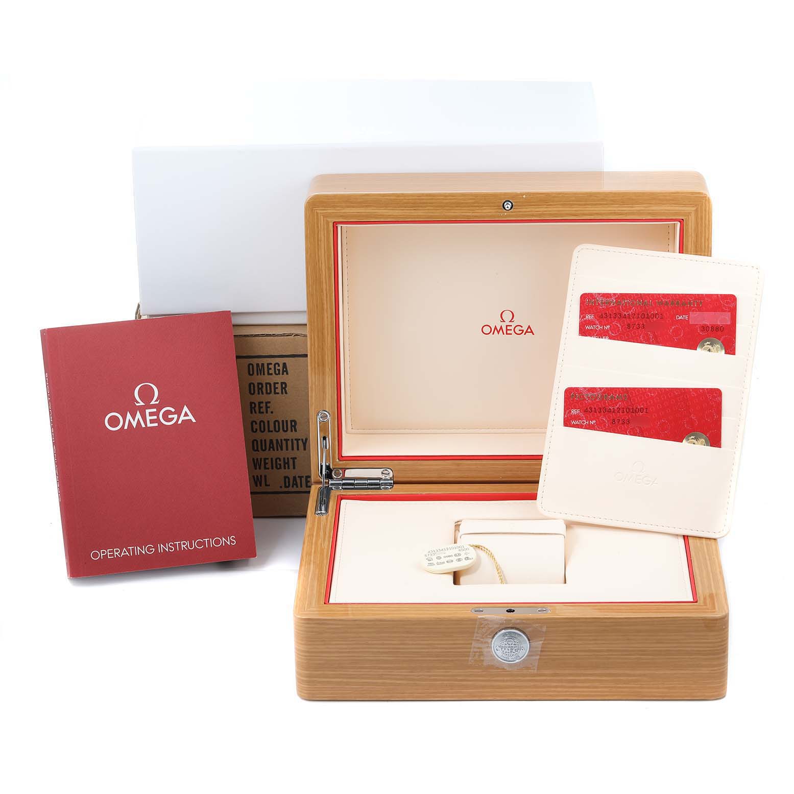 The image shows the open packaging of an Omega De Ville 431.33.41.21.01.001 Men
s Stainless Steel Black Dial 431.33.41.21.01.001 Men
s Stainless Steel Black Dial watch, including a wooden box, operating instructions, and warranty cards.