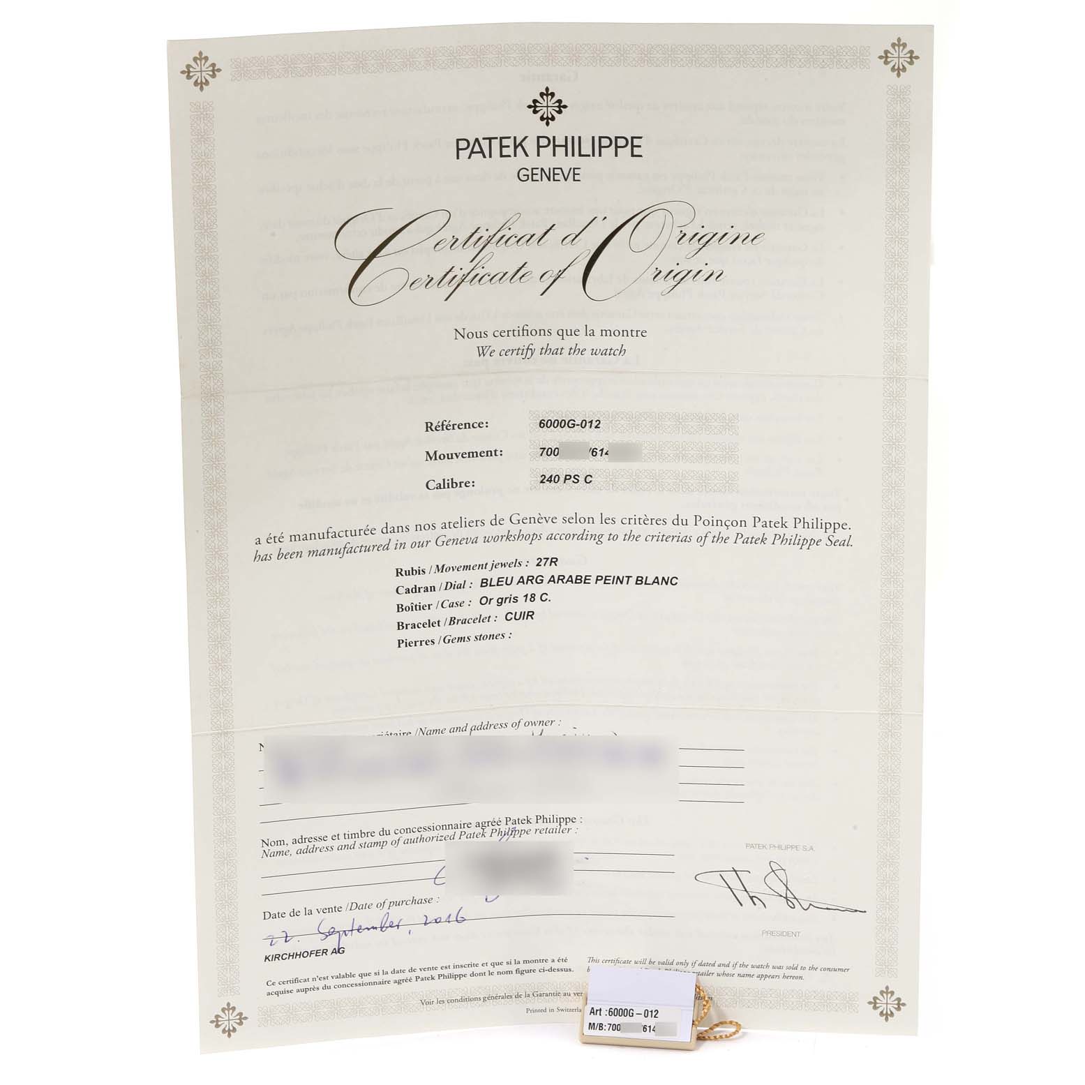 The image shows a Certificate of Origin for a Patek Philippe Calatrava 6000G-012 Men's White Gold Blue Dial 6000G-012 Men's White Gold Blue Dial watch, model 6000G-012, with what appears to be a tag attached.