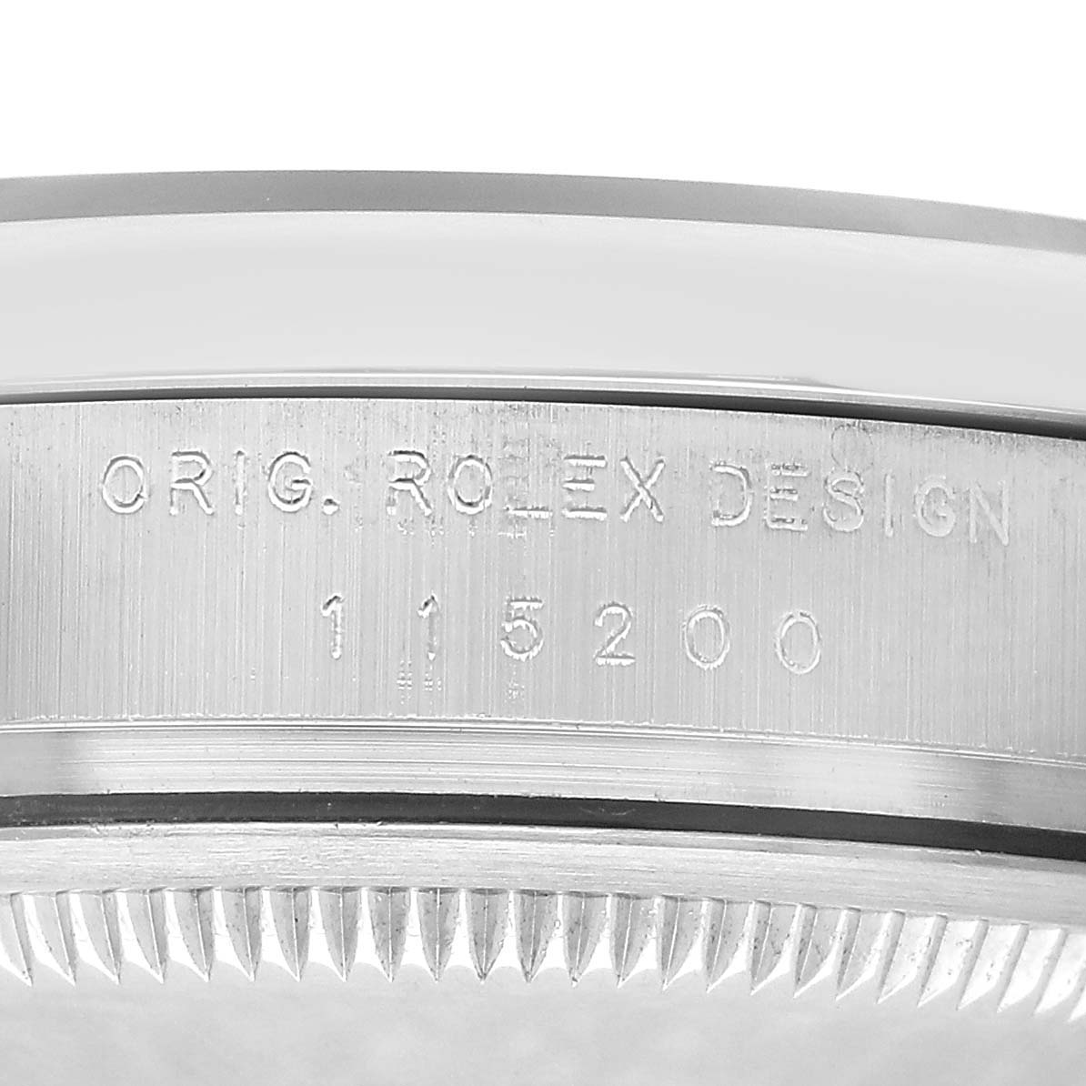 The image shows the side engraving on the case of a Rolex Date 115200 Men's Stainless Steel White Dial model, displaying the design and model number.