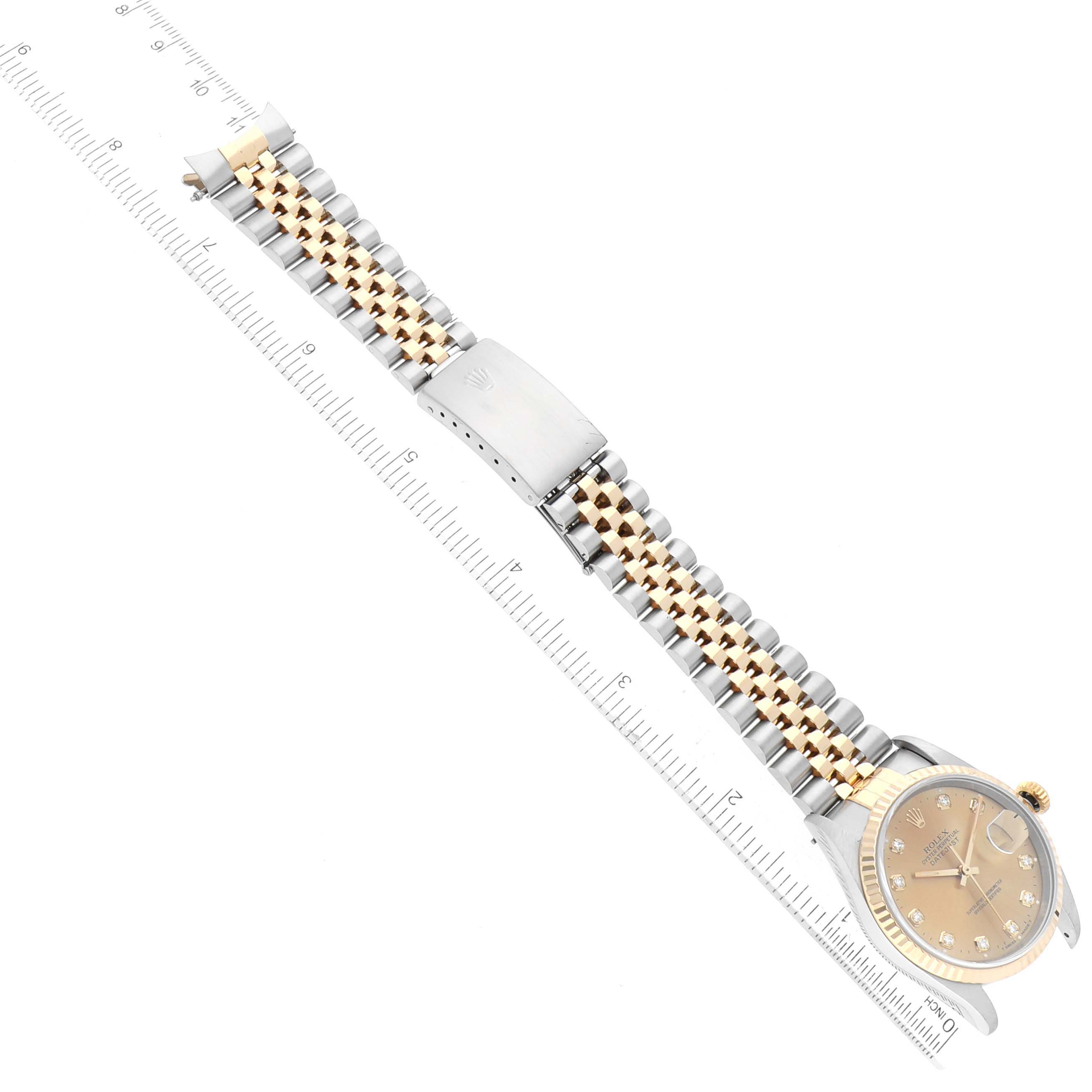 The Rolex Datejust 16233 Men's Steel and Gold (two tone) Champagne Dial 16233 Men's Steel and Gold (two tone) Champagne Dial watch is displayed flat, showcasing its face, bezel, bracelet, and clasp against a ruler for scale.