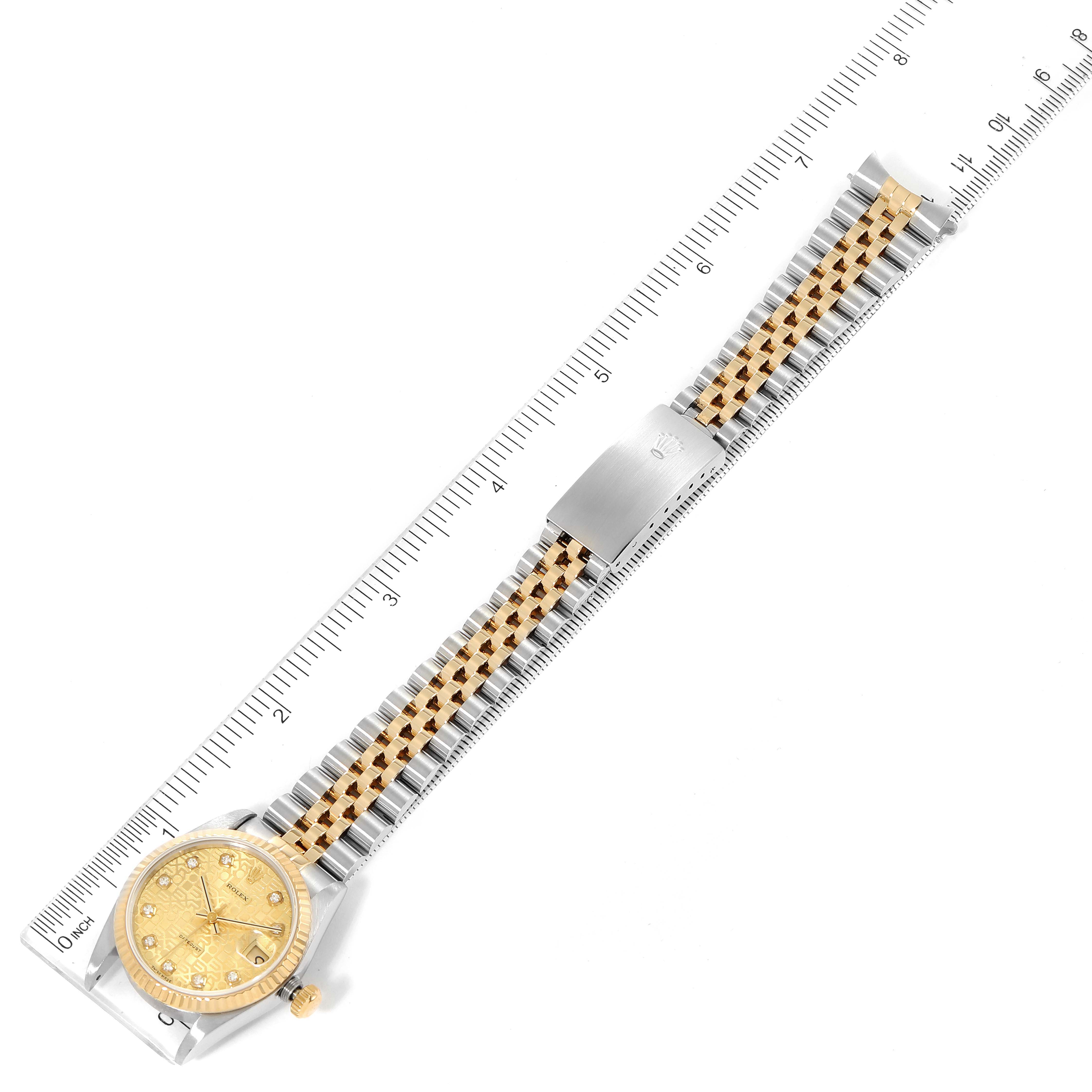 This image shows a top-down view of a Mid-Size Rolex watch with its face, bezel, and bracelet aligned next to a ruler.
