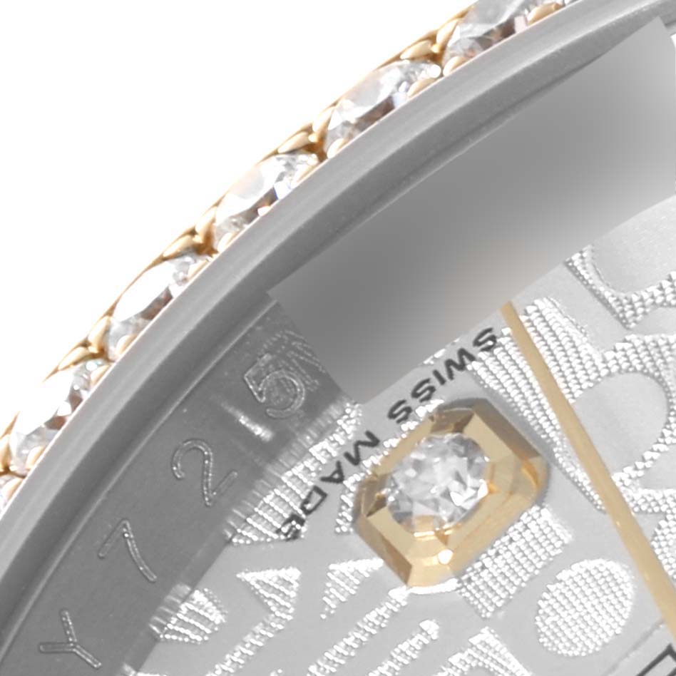 This close-up image of a Rolex Datejust 116243 Men
s Steel and Gold (two tone) Silver Dial 116243 Men
s Steel and Gold (two tone) Silver Dial watch shows a section of the diamond-studded bezel and part of the dial with a diamond marker.