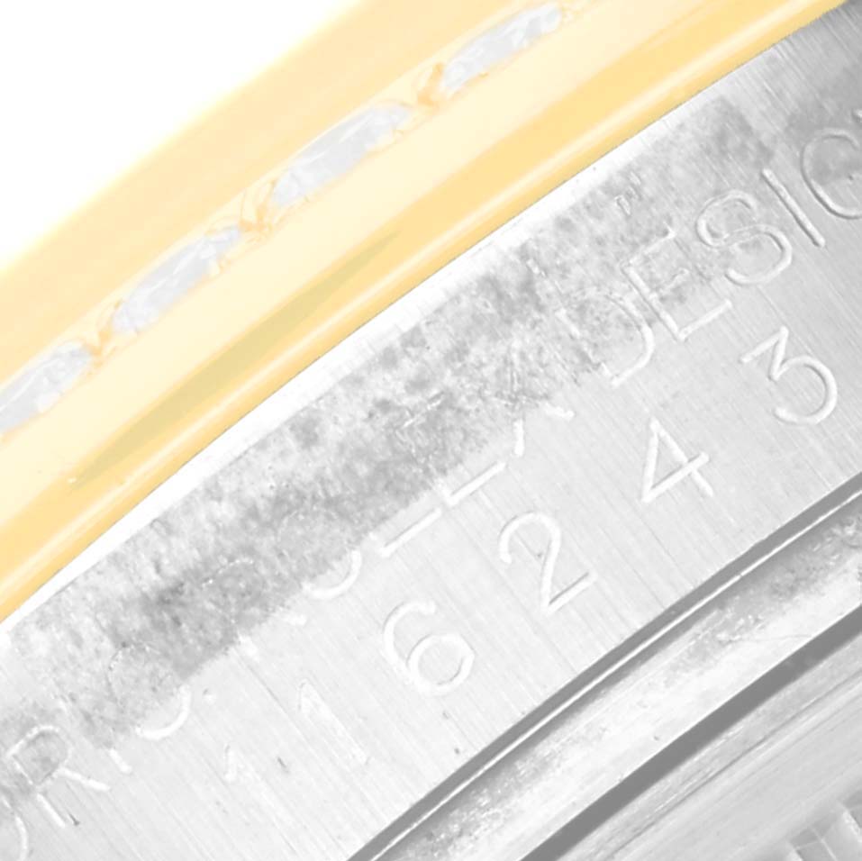 The image shows a close-up of the Rolex Datejust 116243 Men
s Steel and Gold (two tone) Silver Dial 116243 Men
s Steel and Gold (two tone) Silver Dial watch case with part of the bezel and engraving visible.