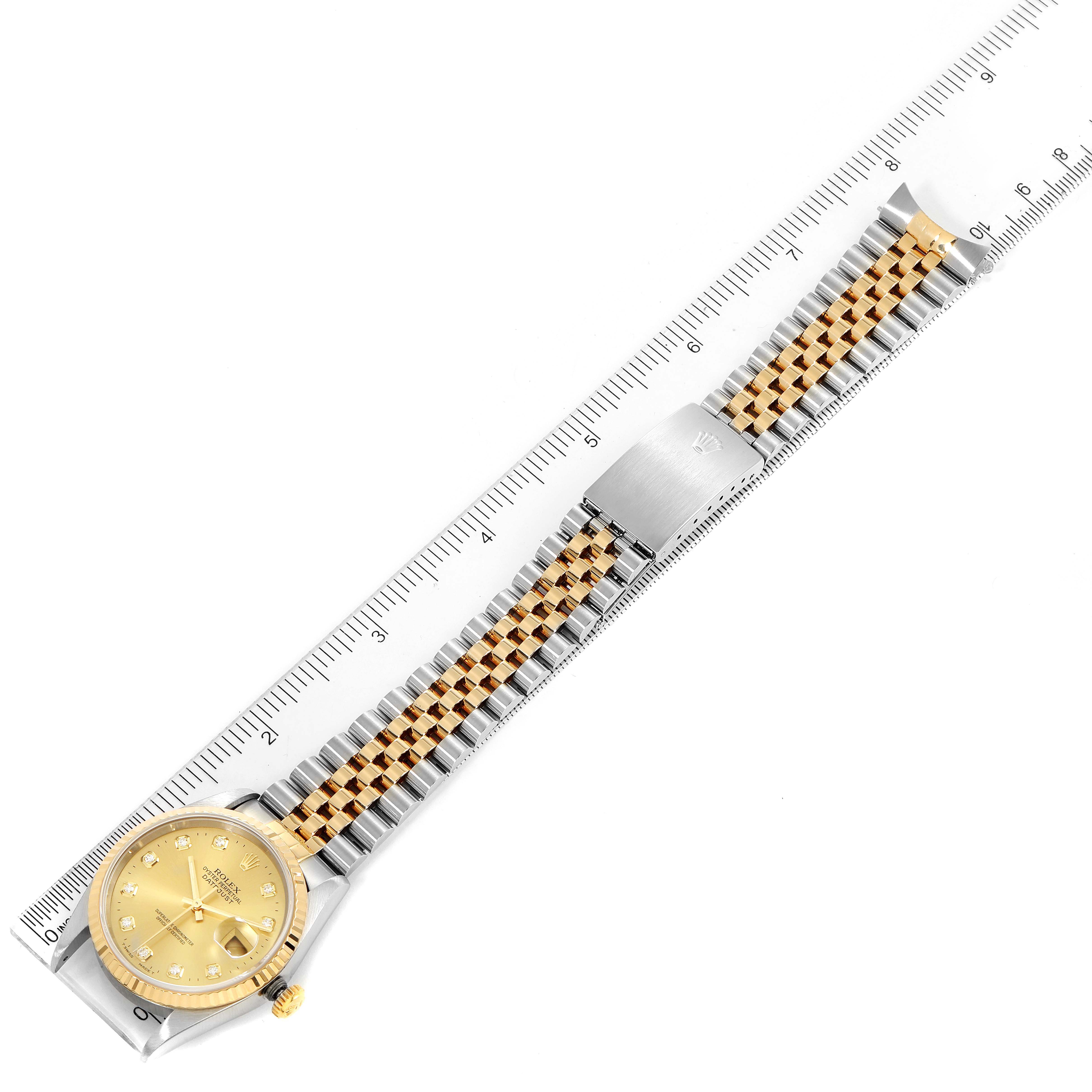 The image shows a Rolex Datejust 16233 Men's Steel and Gold (two tone) Champagne Dial 16233 Men's Steel and Gold (two tone) Champagne Dial model with a two-tone bracelet and a ruler for scale, viewed from above.