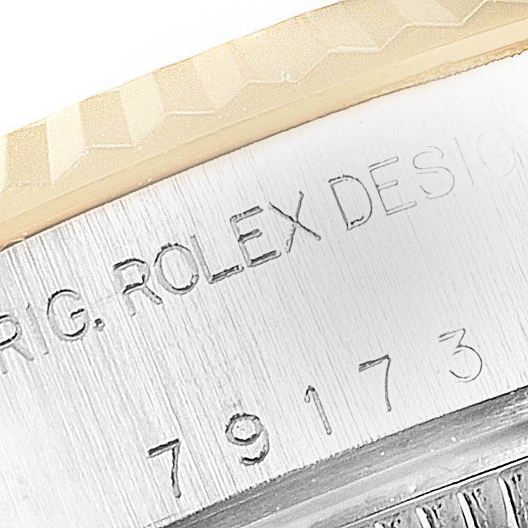 The image shows an extreme close-up of the casing of a Rolex Datejust 79173 Women
s Steel and Gold (two tone) Champagne Dial 79173 Women
s Steel and Gold (two tone) Champagne Dial watch, highlighting the engraved text and part of the bezel.
