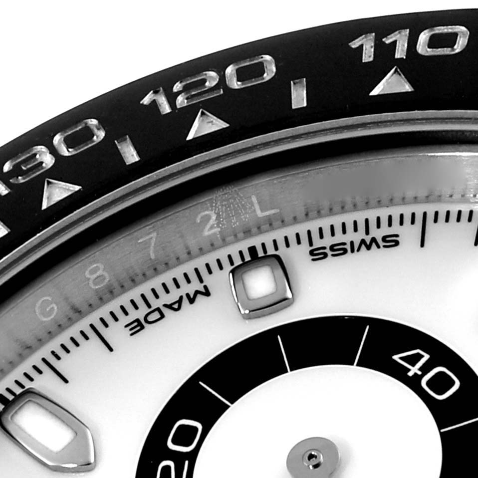 This close-up image of a Rolex Daytona 116500 Men's Stainless Steel White Dial 116500 Men's Stainless Steel White Dial watch shows the bezel, part of the dial, and some markings.
