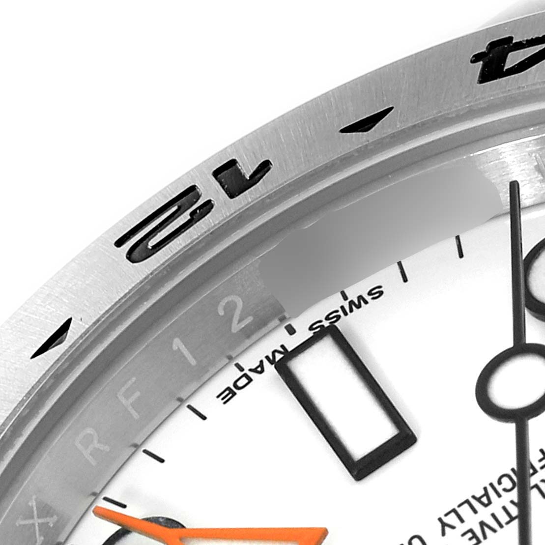 This close-up angle of the Rolex Explorer 216570 Men's Stainless Steel White Dial 216570 Men's Stainless Steel White Dial watch shows part of the bezel, dial, and the 12 o'clock marker.