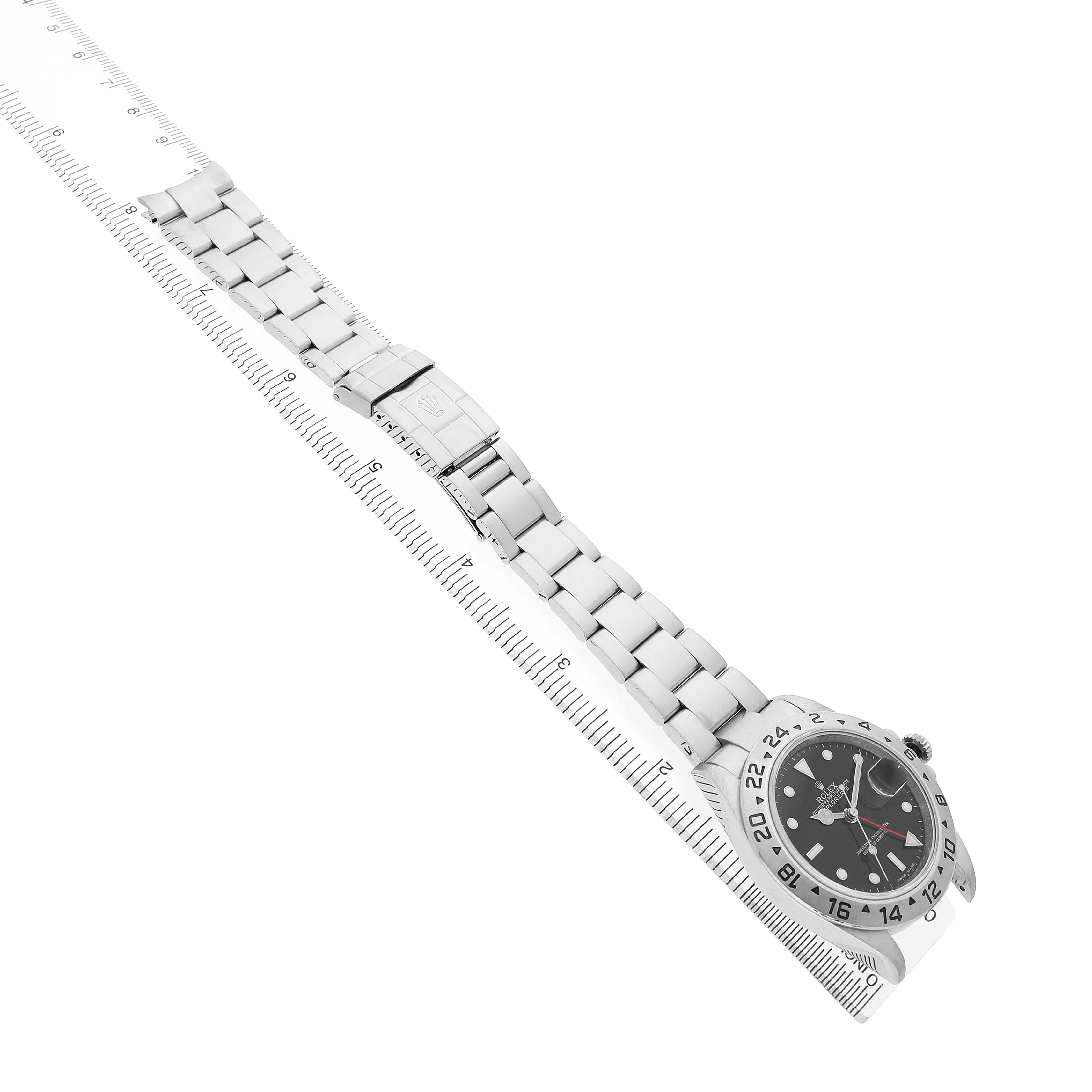 The image shows a Rolex Explorer 16570 T Men's Stainless Steel Black Dial watch from an angled top view, highlighting the bracelet, clasp, and face alongside a ruler for scale.