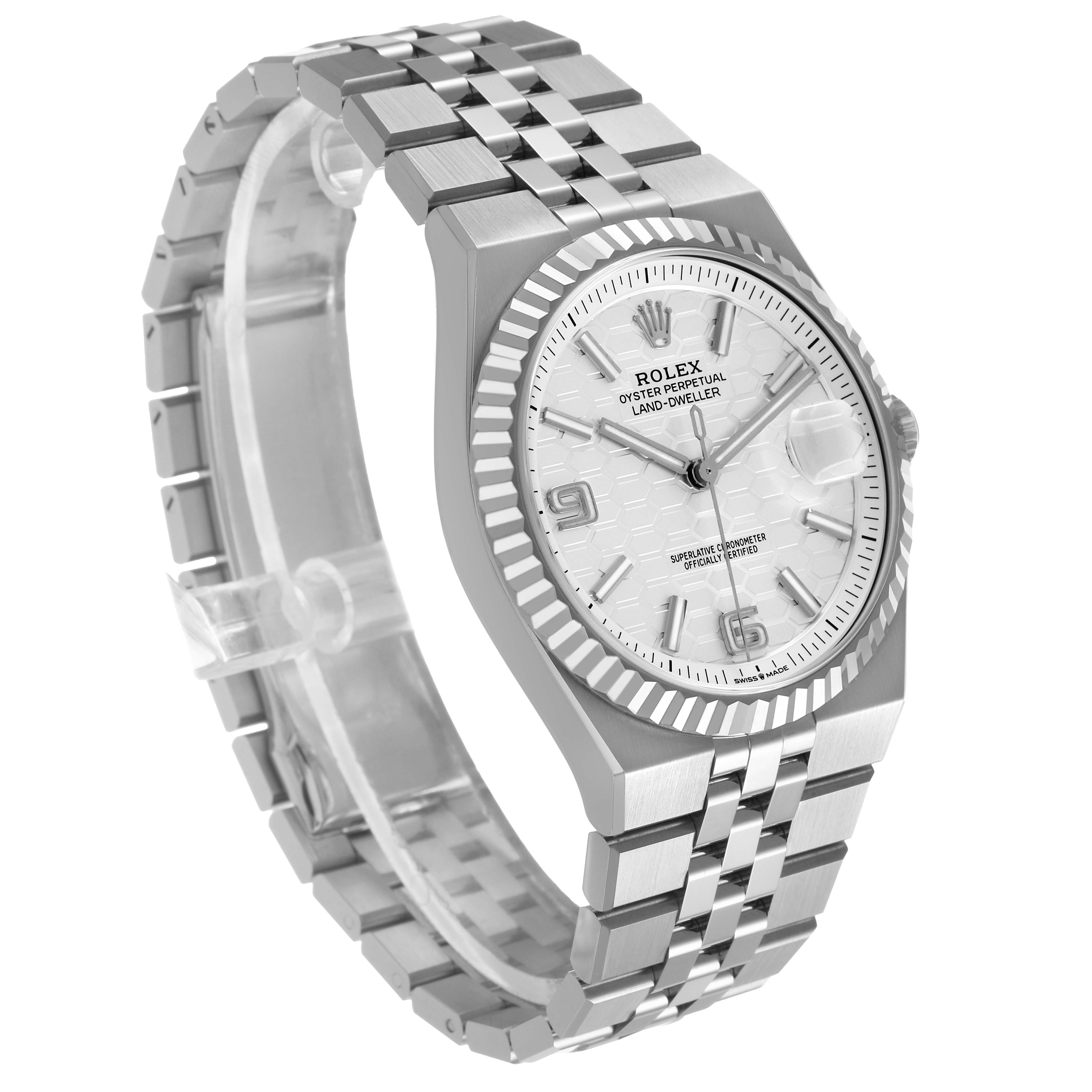 The Rolex Land-Dweller is shown at an angle displaying the face, bezel, crown, and part of the metal bracelet.