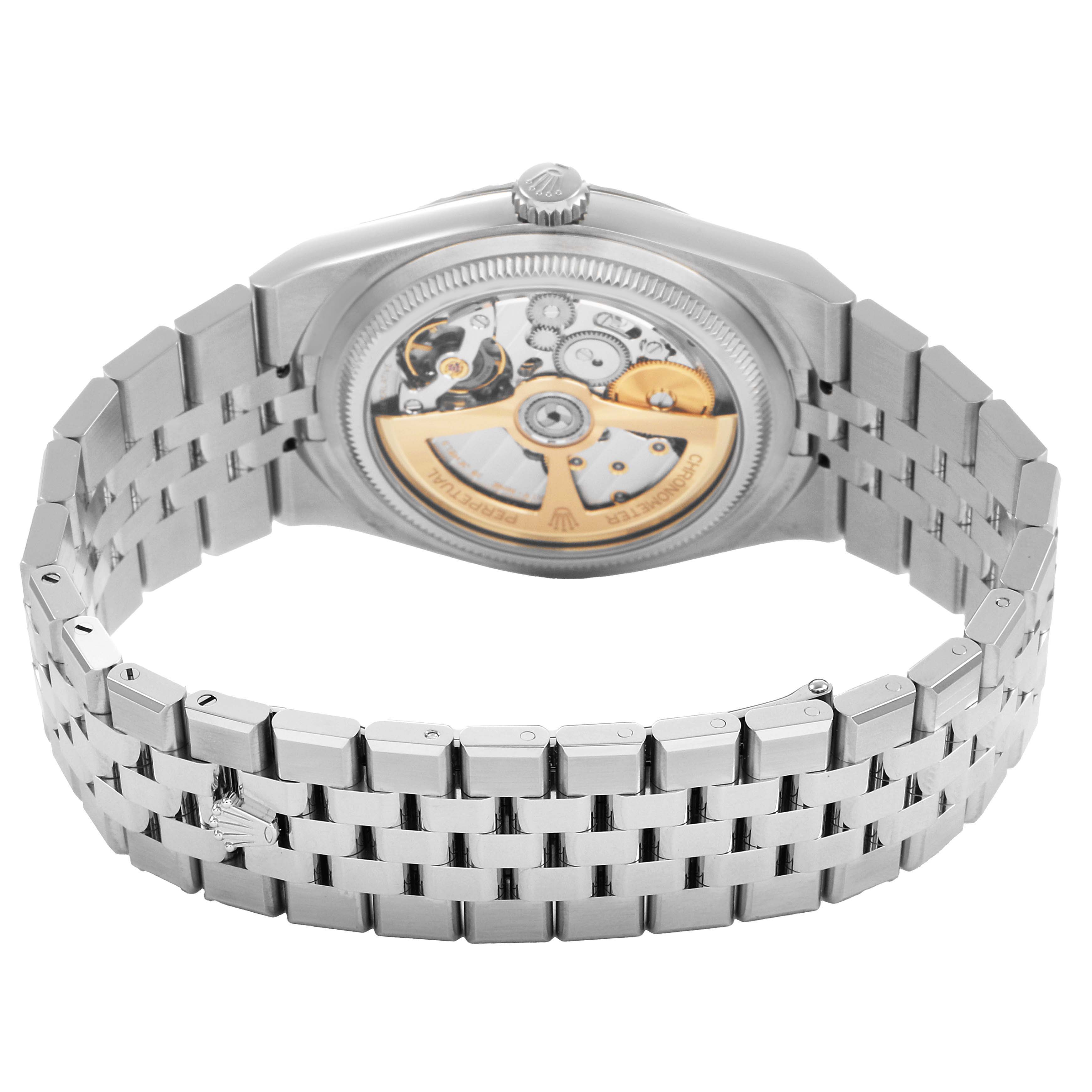 The image shows the back of a Rolex Land-Dweller watch, highlighting the movement and bracelet.