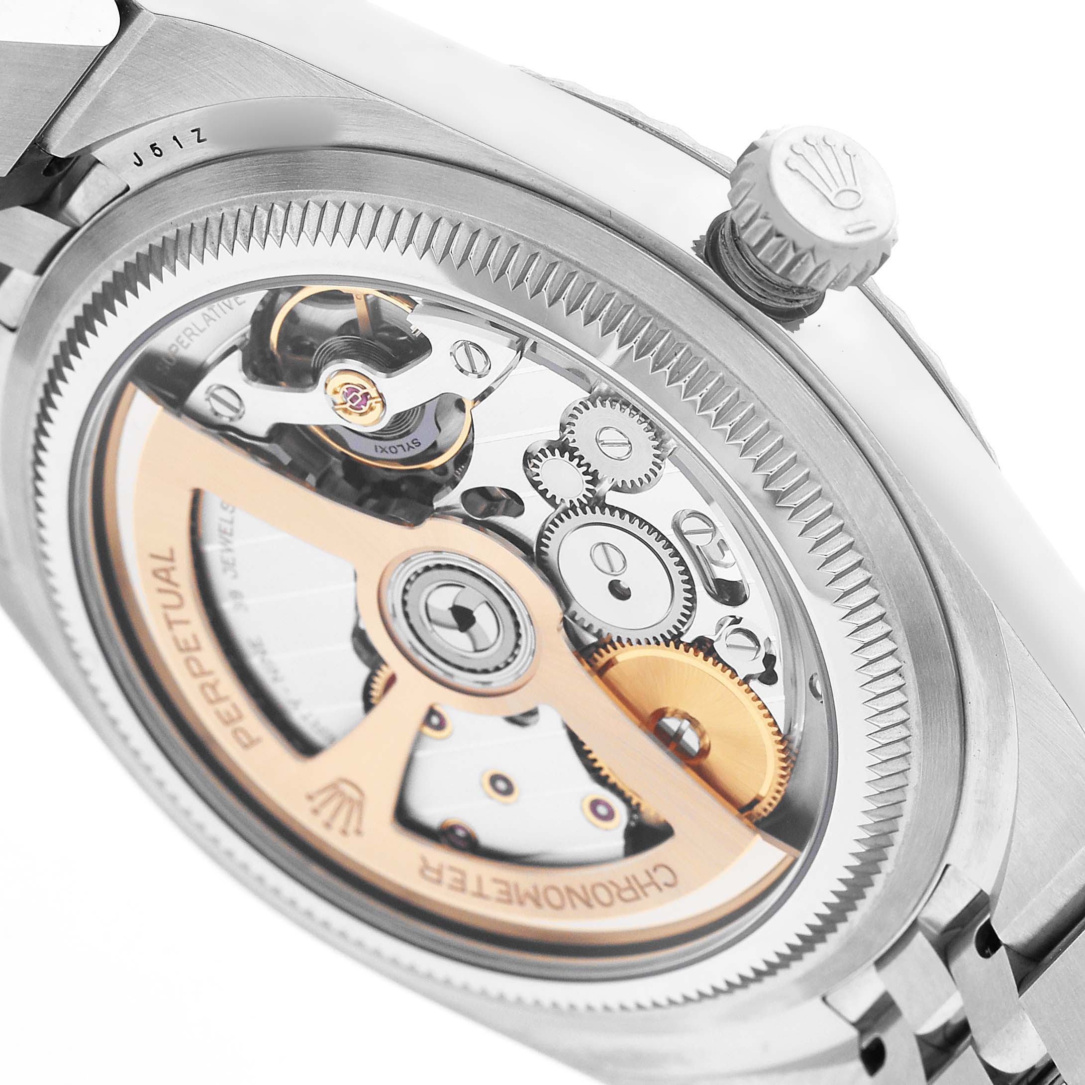 The image shows the back of the Rolex Land-Dweller, highlighting its intricate movement and winding crown.