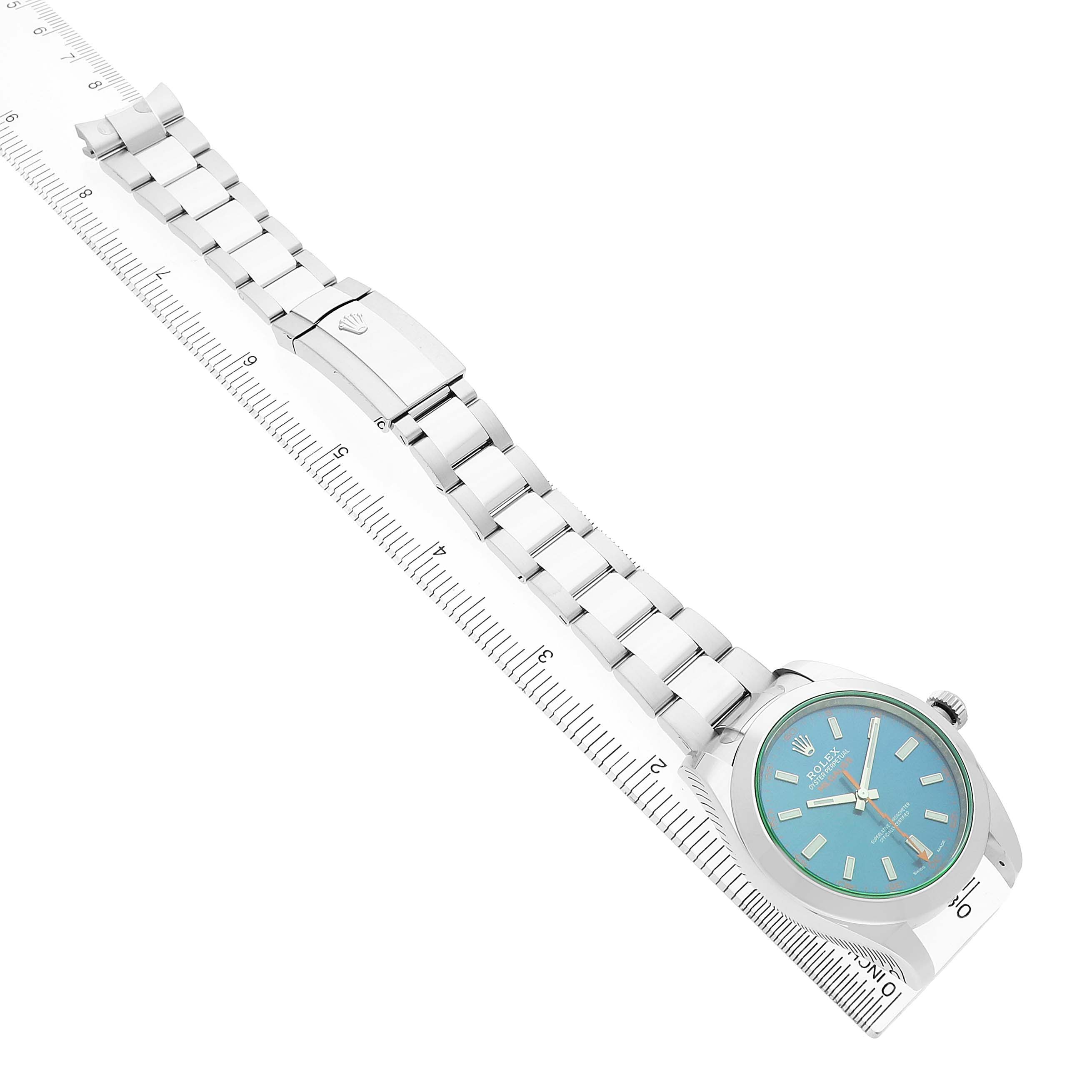 The Rolex Milgauss M116400GV Men's Stainless Steel Blue Dial watch is shown at an oblique angle, displaying the face, bracelet, and clasp alongside a ruler.