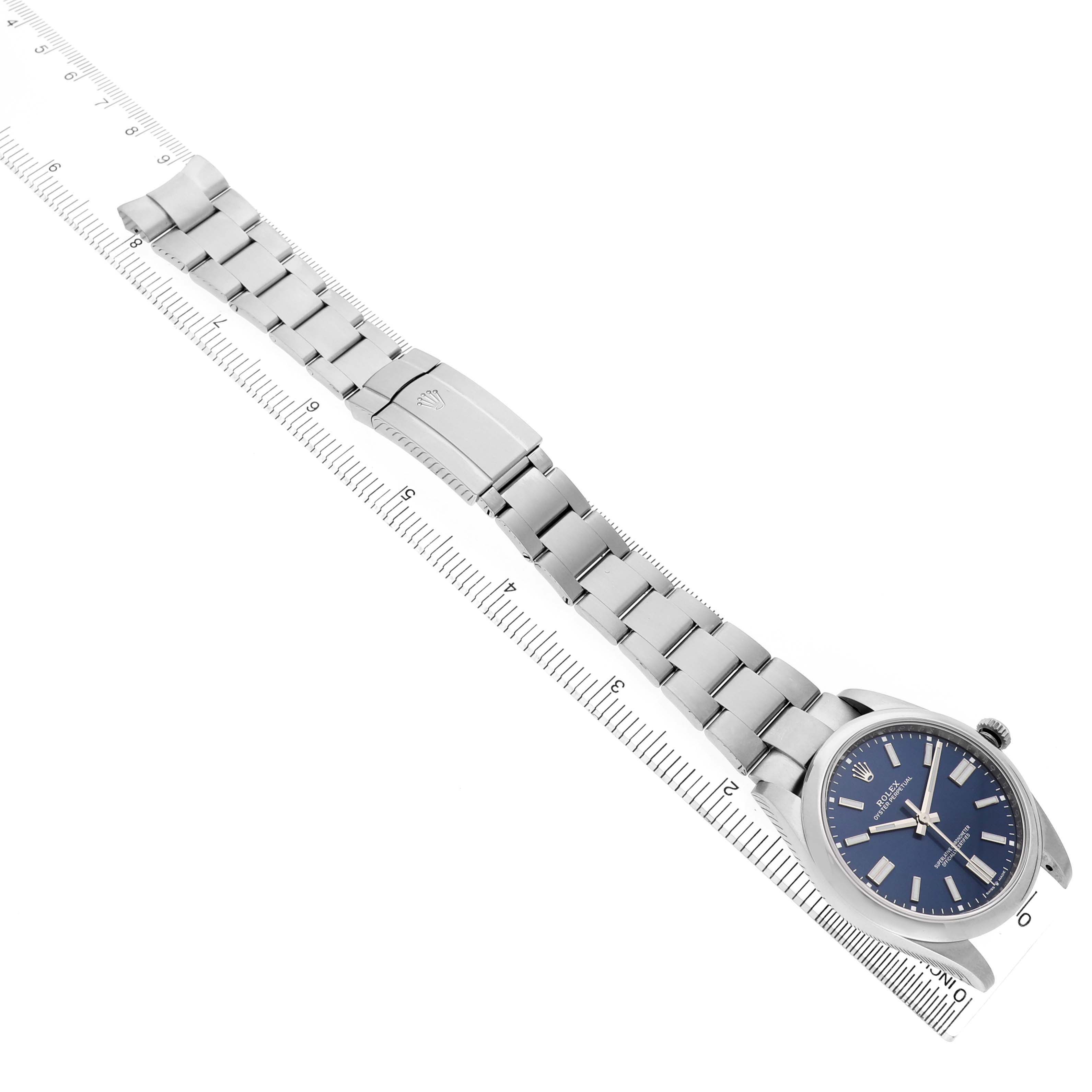 The Rolex Oyster Perpetual 124300 Men's Stainless Steel Blue Dial watch is shown from a top-down angle, highlighting the face, bracelet, and clasp.
