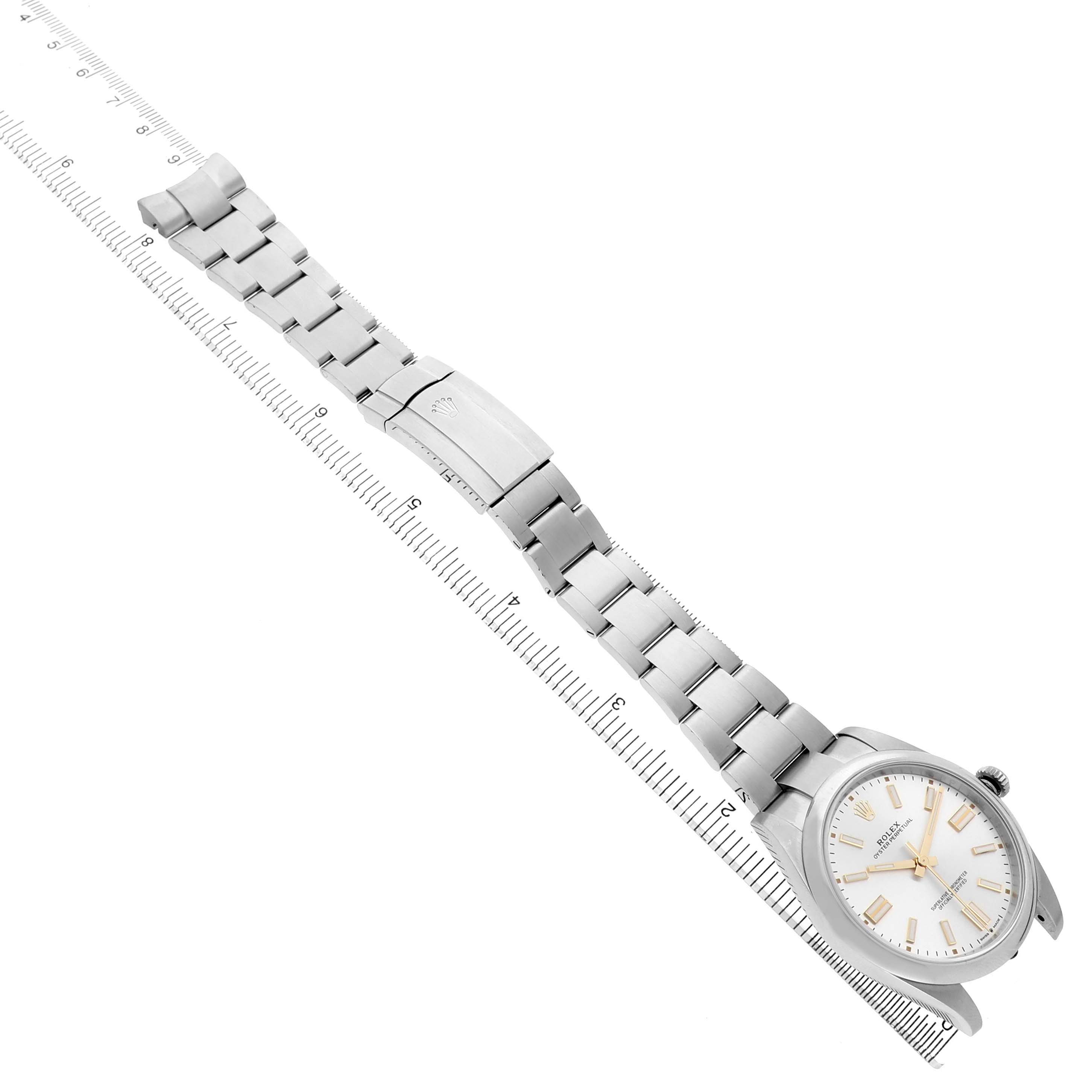 The Rolex Oyster Perpetual 124300 Men's Stainless Steel Silver Dial watch is displayed diagonally, showing the face, bracelet, and clasp alongside a measuring ruler.