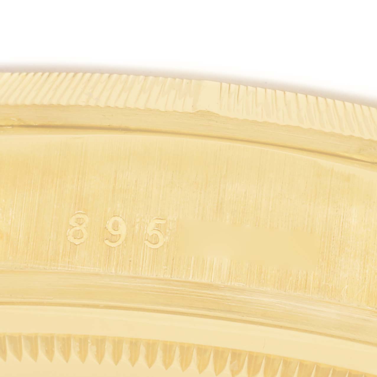 The image shows a close-up of the side of a Rolex President 18078 Men
s Yellow Gold Silver Dial 18078 Men
s Yellow Gold Silver Dial watch
s gold bezel with engraved numbers.