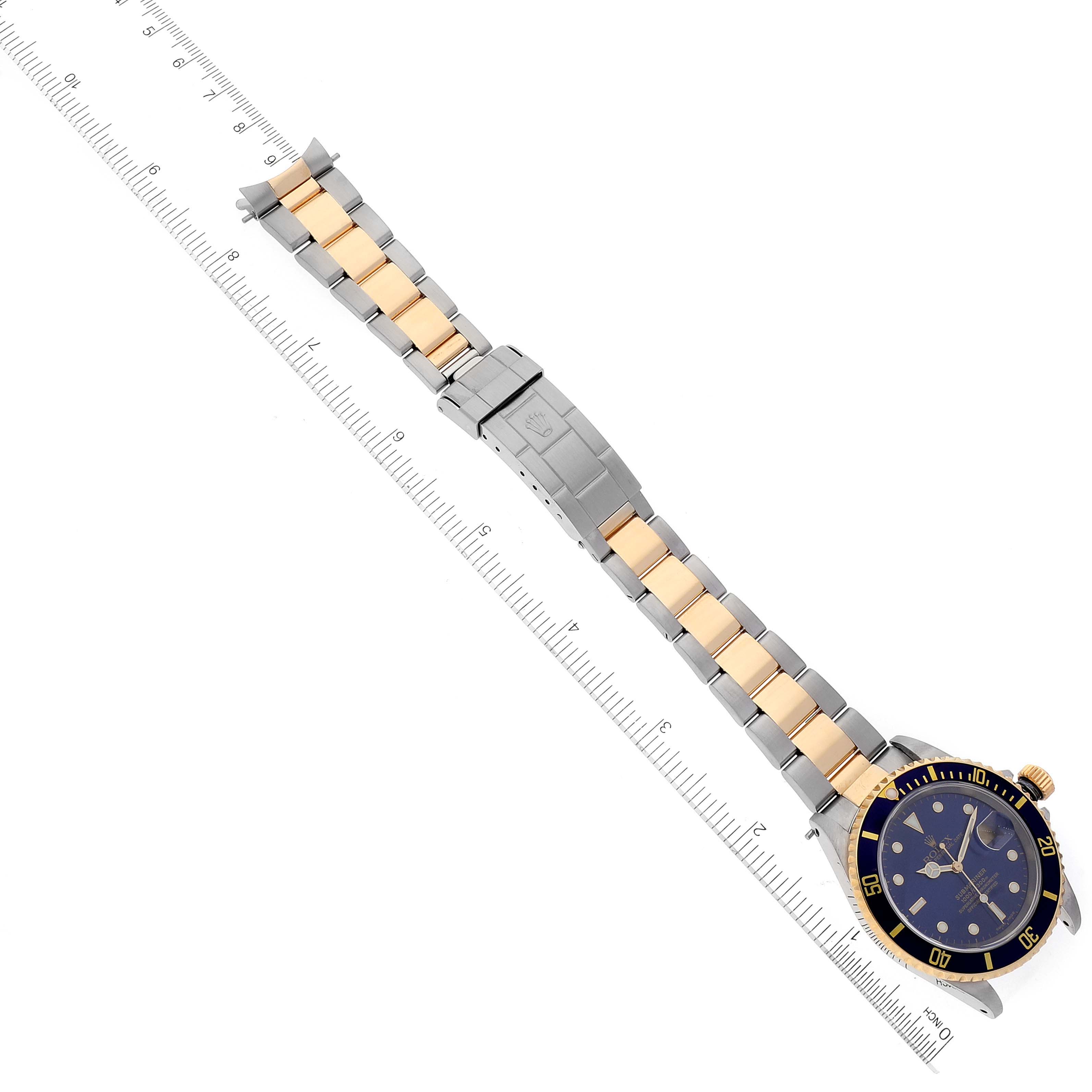 The image shows a Rolex Submariner 16613 Men
s Steel and Gold (two tone) Blue Dial 16613 Men
s Steel and Gold (two tone) Blue Dial watch laid flat with its face, bezel, and two-tone metal bracelet visible, measured against a ruler.