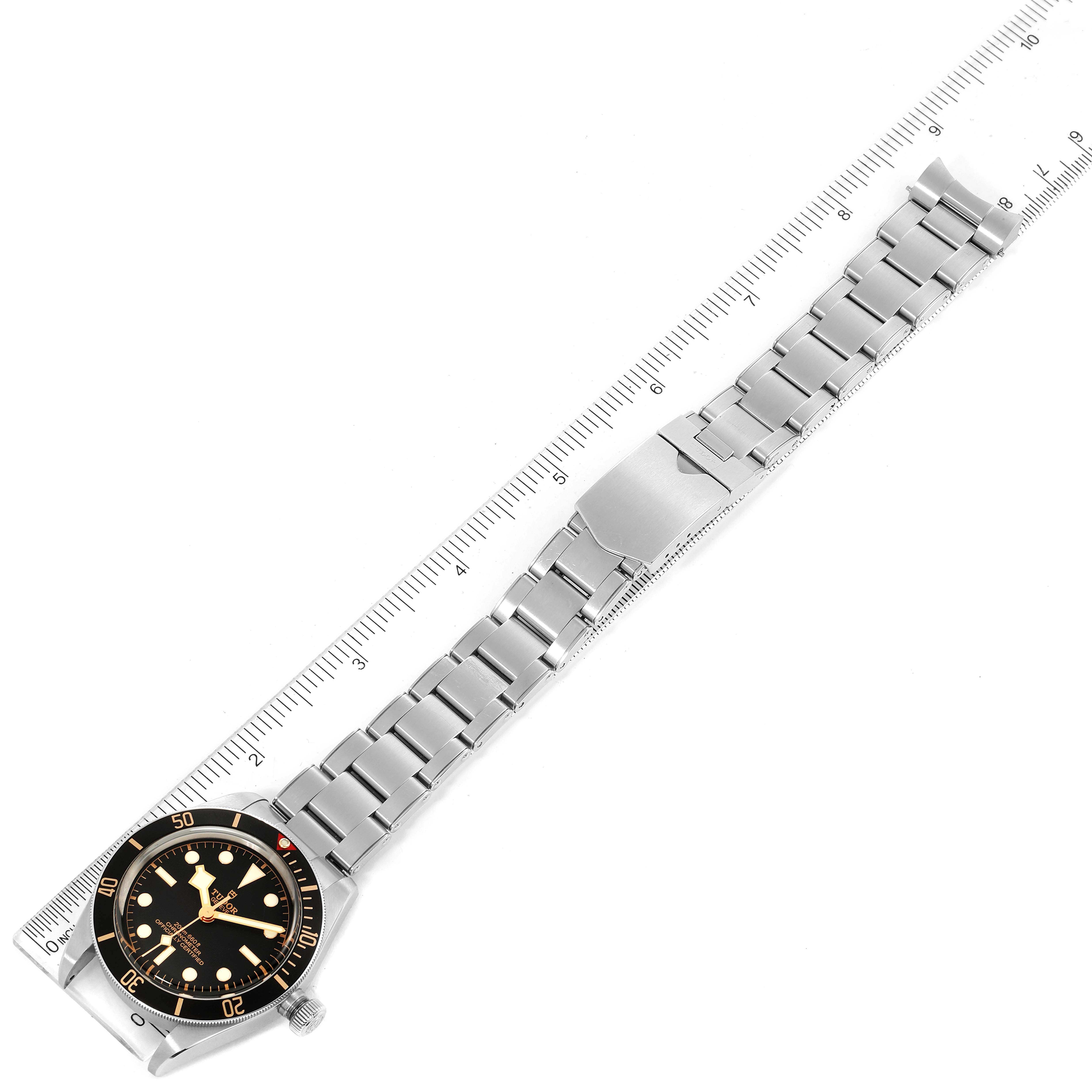 This image shows a Tudor Heritage Black Bay 79030N Men
s Stainless Steel Black Dial 79030N Men
s Stainless Steel Black Dial watch laid flat, featuring its face, bracelet, and clasp, with a ruler alongside.