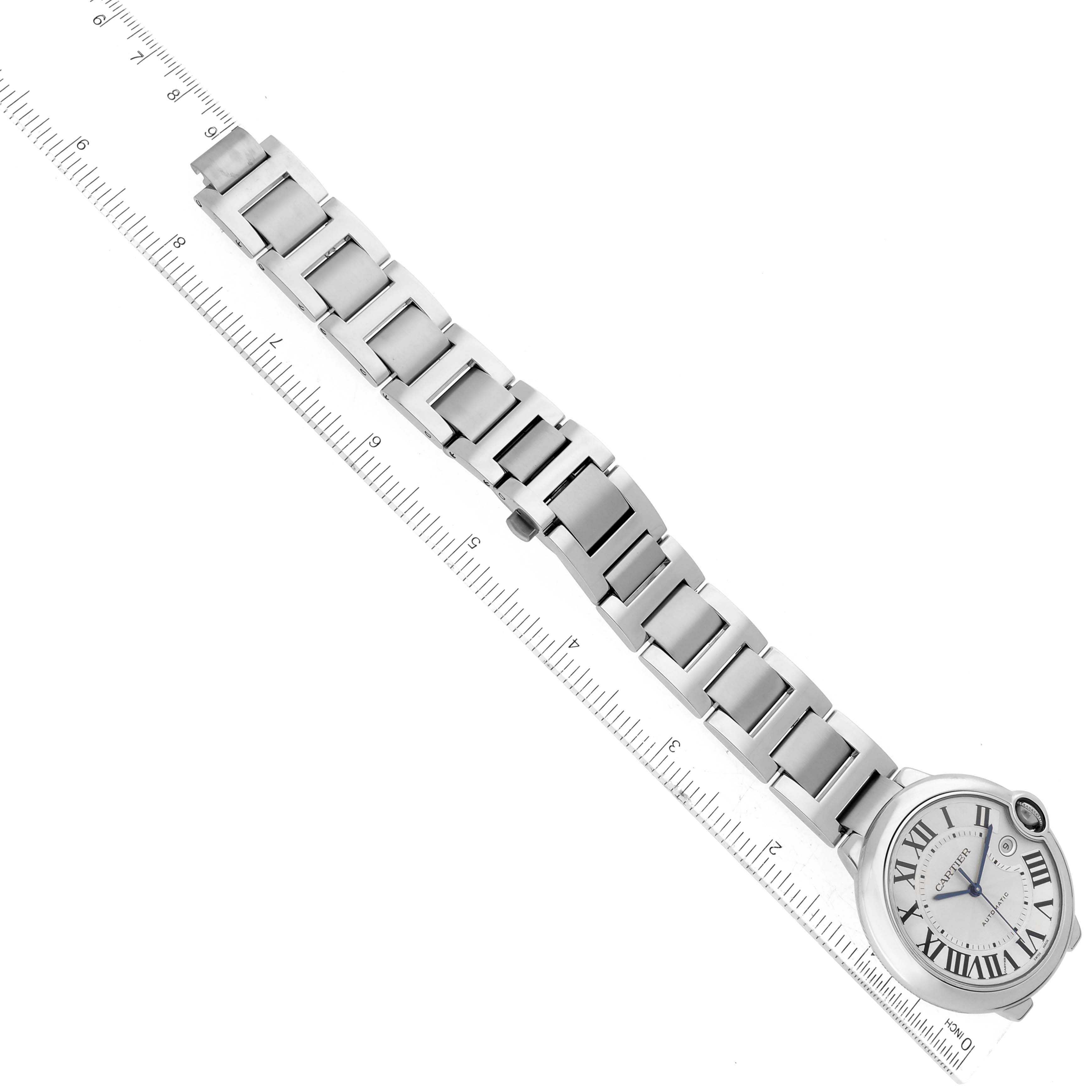 The image shows the Ballon Bleu by Cartier at a tilted angle, displaying its face, bracelet, and clasp against a ruler for scale.