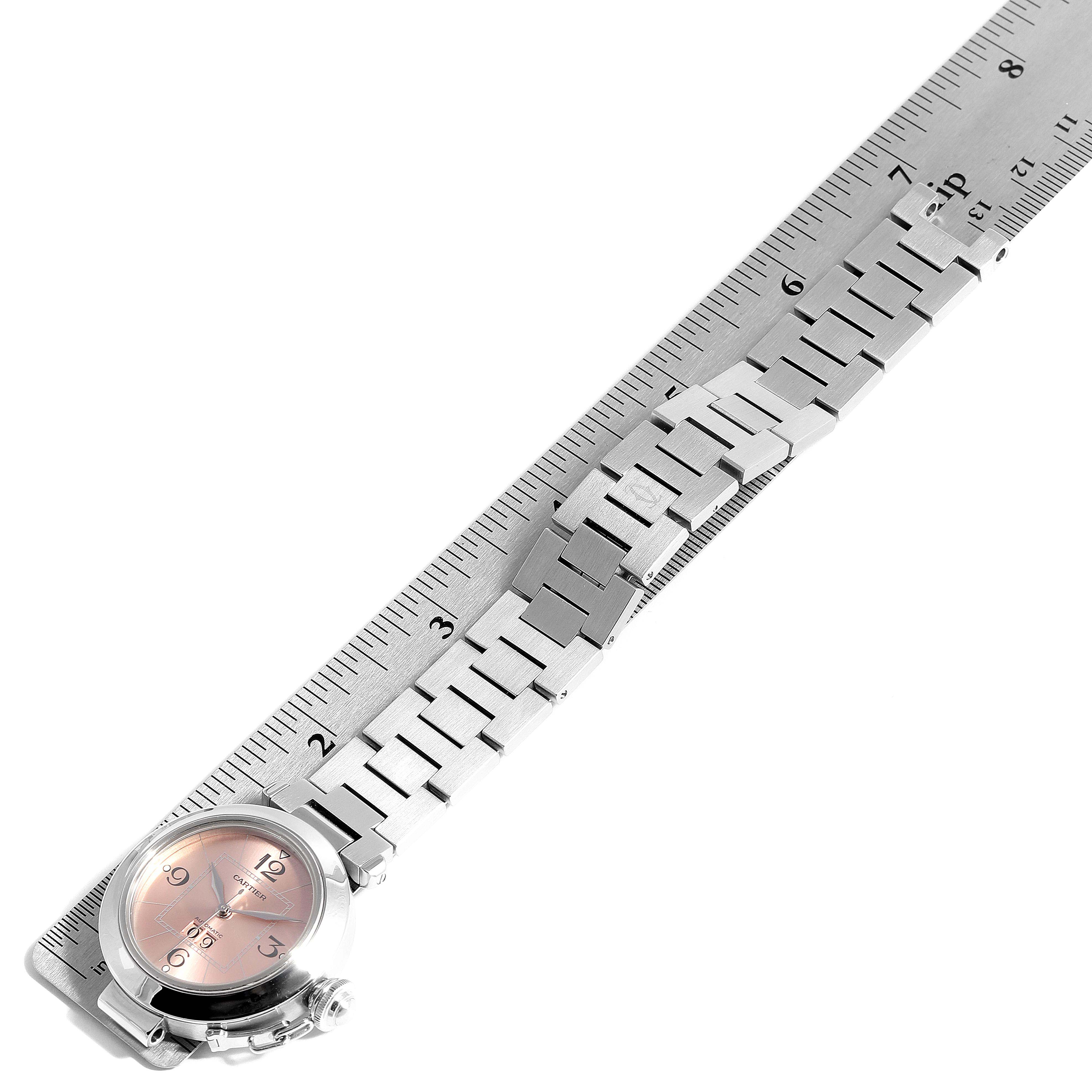 The image shows the Cartier Pasha W31058M7  Women's Stainless Steel Pink Dial W31058M7  Women's Stainless Steel Pink Dial model watch from a top-down angle, placed alongside a ruler displaying both the watch face and metal bracelet.