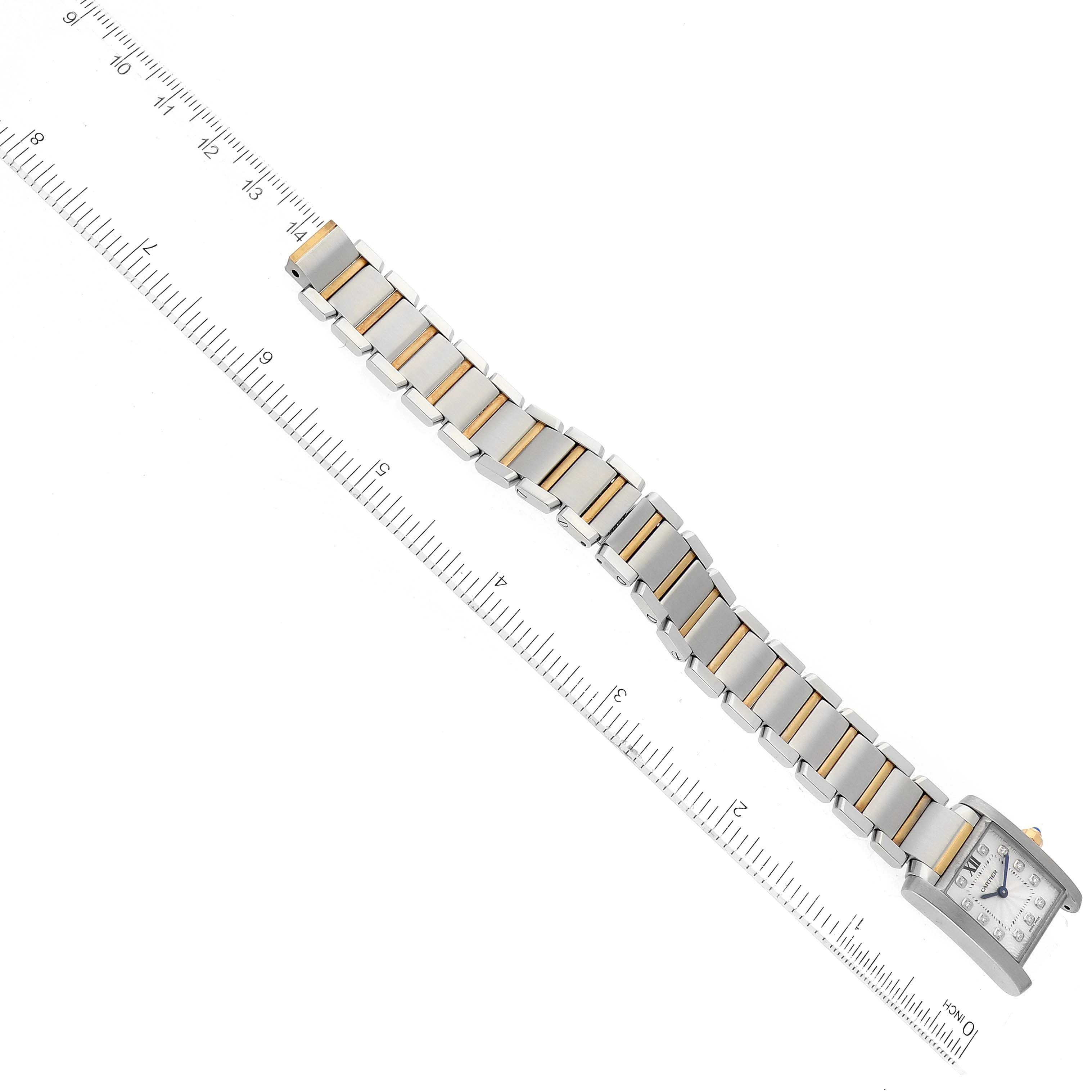 The Tank Française model by Cartier is shown from above, featuring its stainless steel and gold bracelet alongside a ruler for scale.