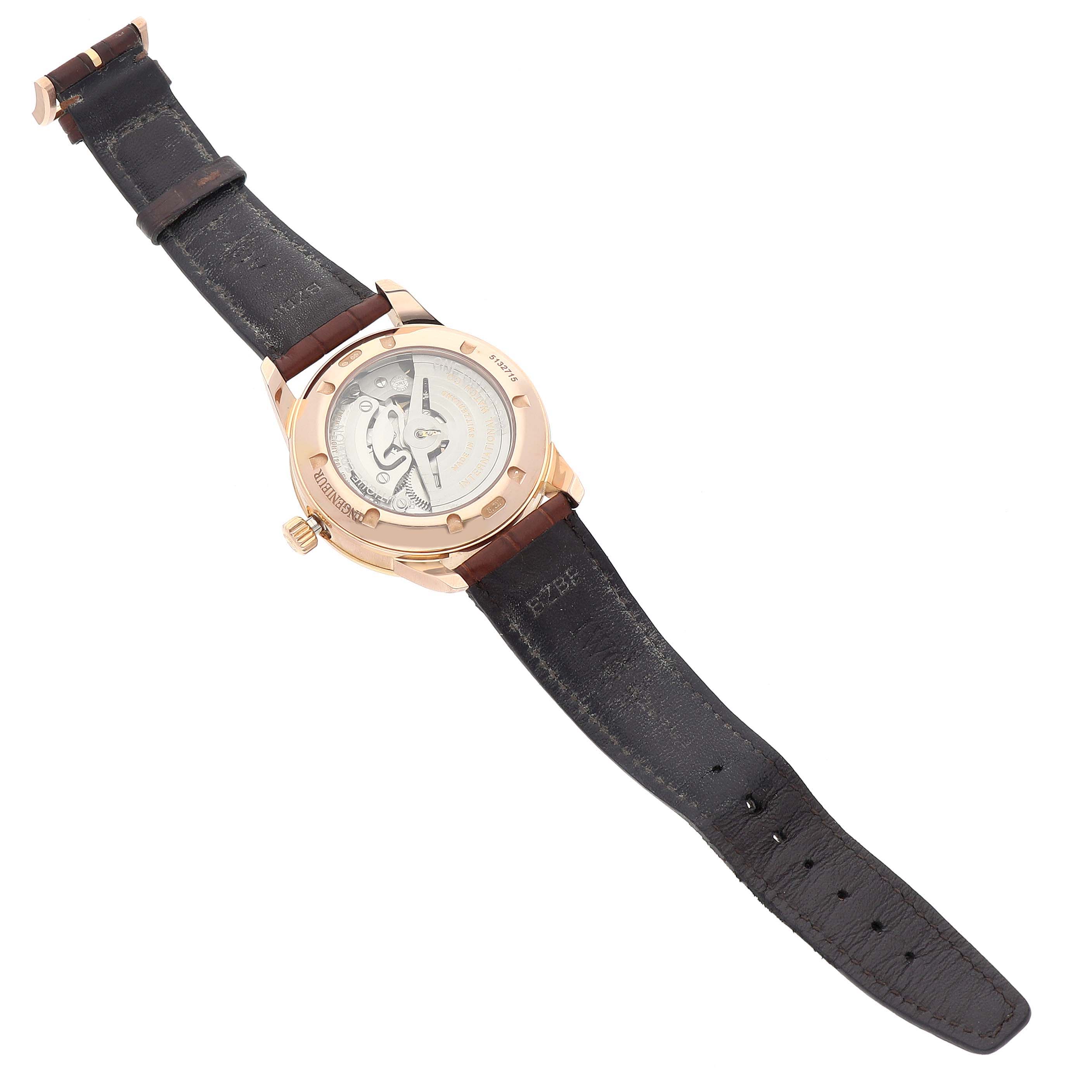 The IWC Ingenieur IW323312 Men's Rose Gold Brown Dial watch is shown from the back at an angle, displaying the movement and leather strap.